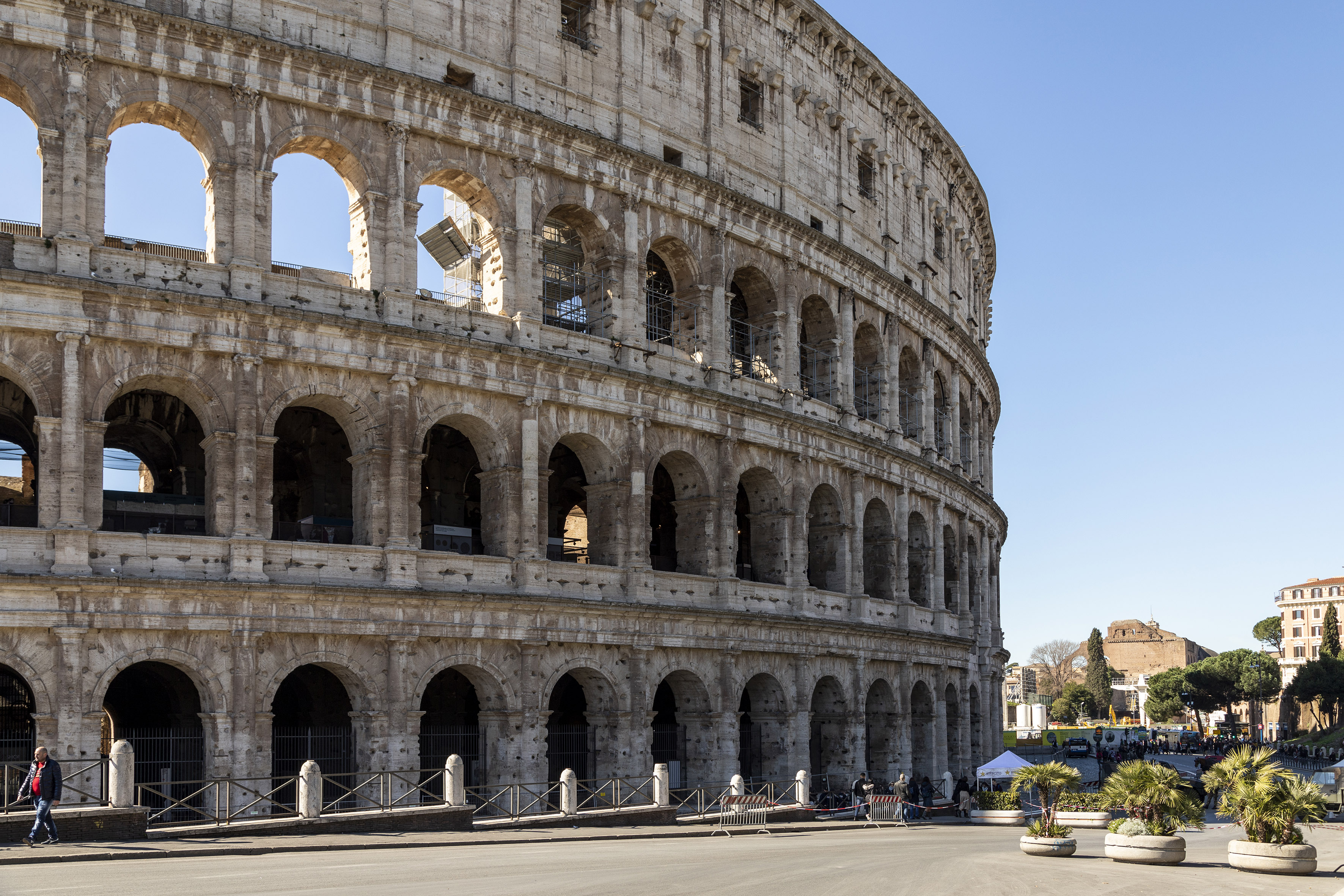 a large stone building with many arches with Colosseum in the background