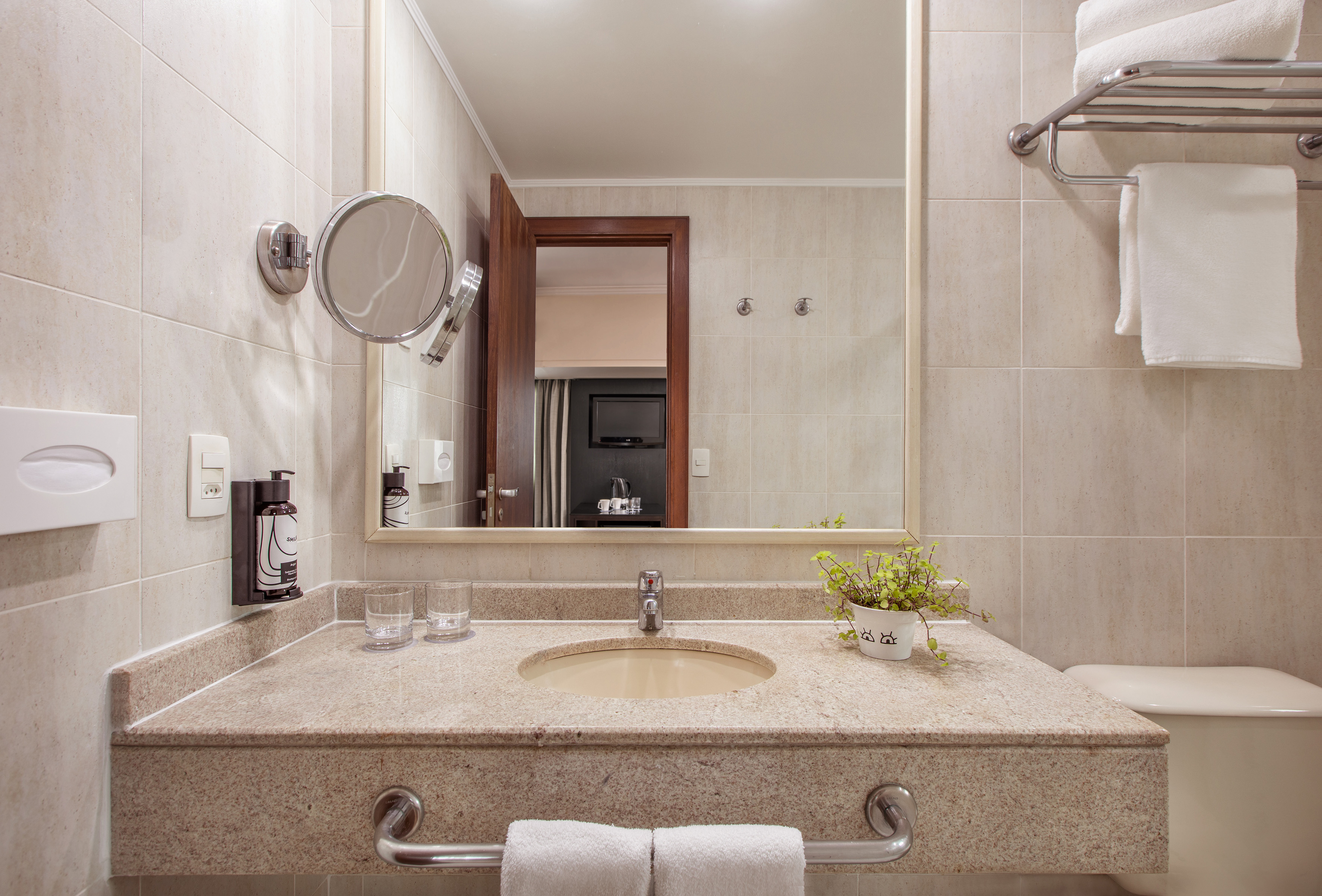 Hotel bathroom vanity with granite counter, integrated sink, mirror, and white towels.