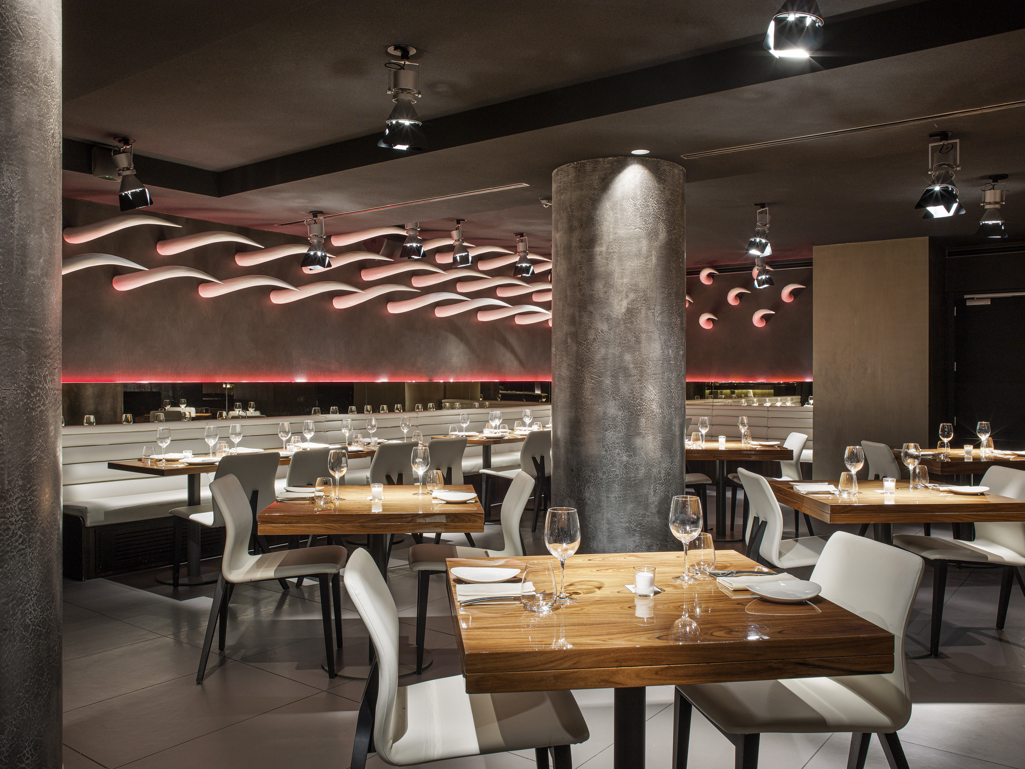 Modern restaurant: Red accent lighting, wood tables, white chairs, dark ambiance.