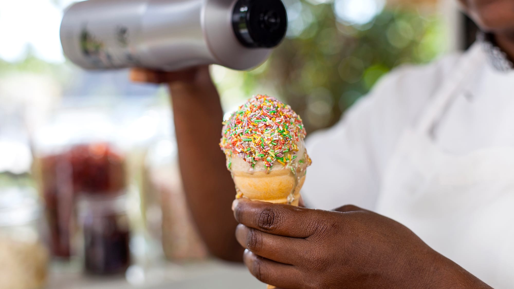 a person holding an ice cream cone with sprinkles
