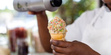a person holding an ice cream cone with sprinkles