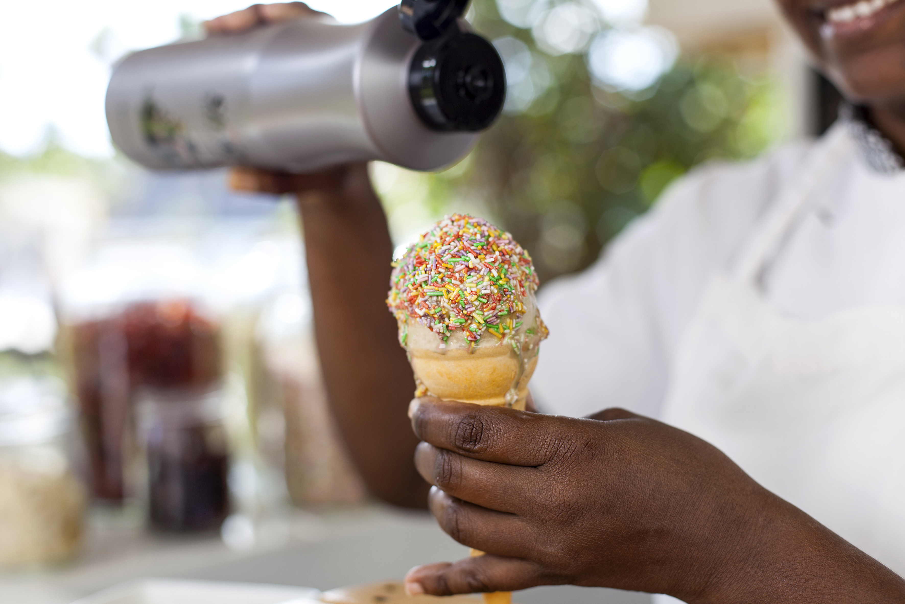 a person holding an ice cream cone with sprinkles