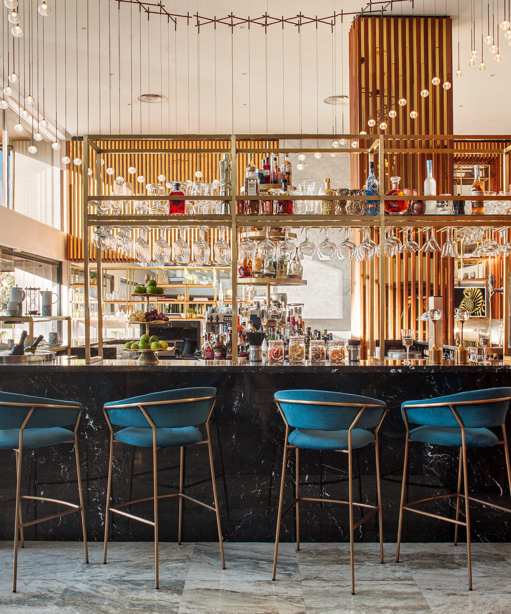 a bar with blue chairs and a shelf with wine glasses