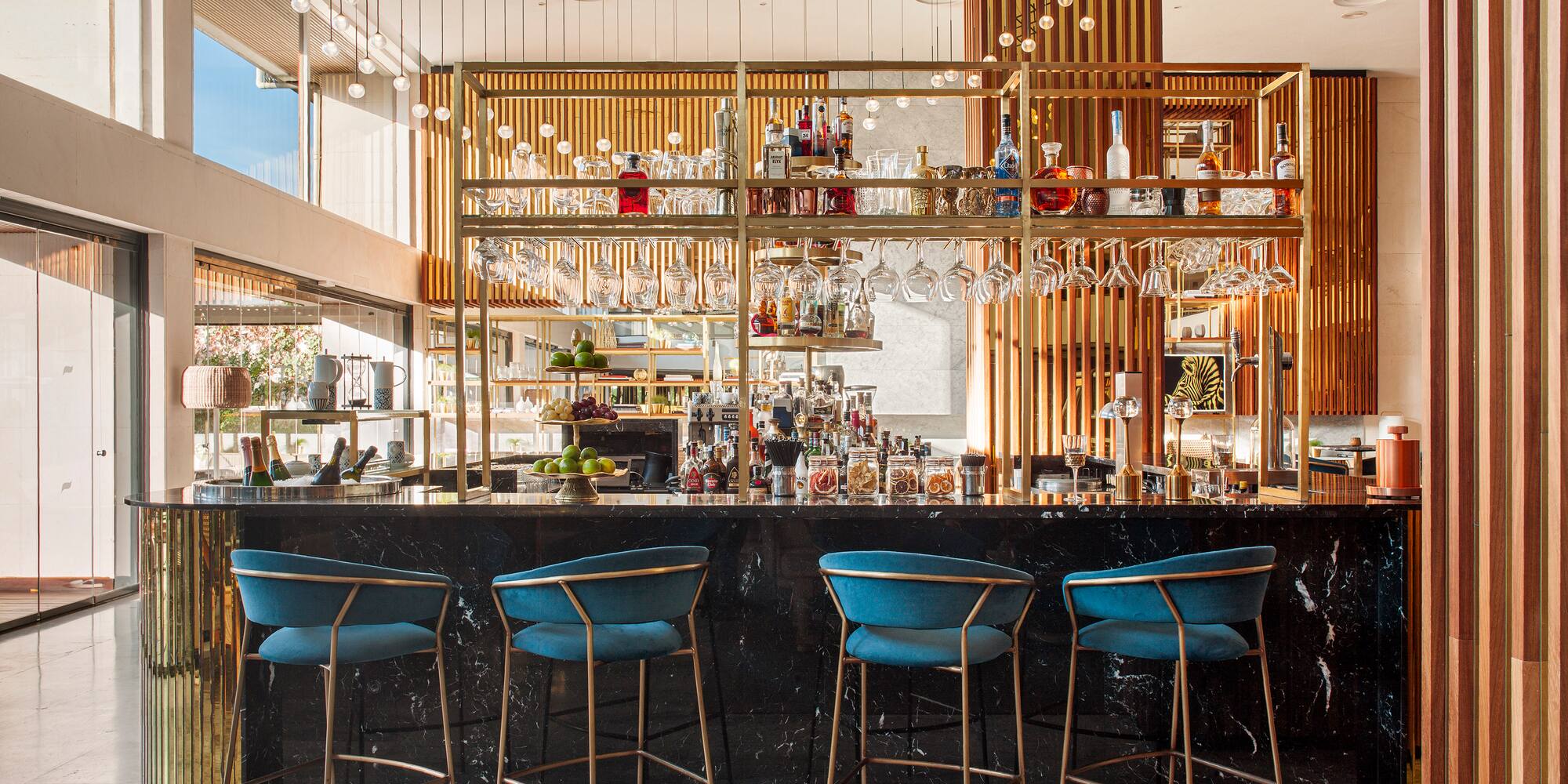 a bar with blue chairs and a shelf with wine glasses