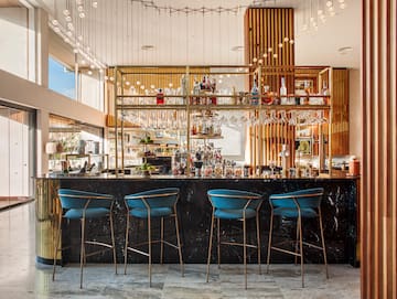 a bar with blue chairs and a shelf with wine glasses