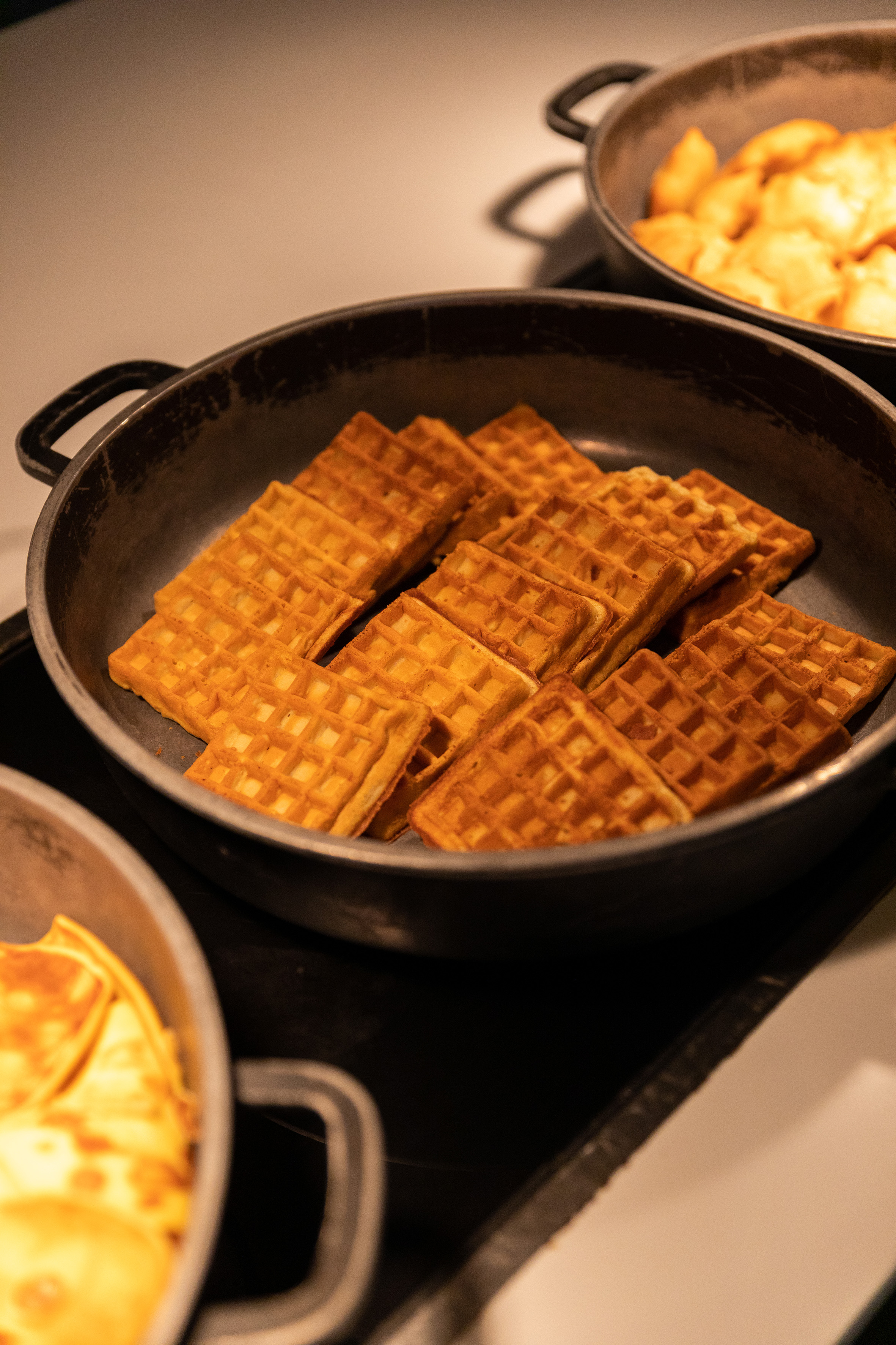Golden brown waffles in a hot serving pan at a breakfast buffet.