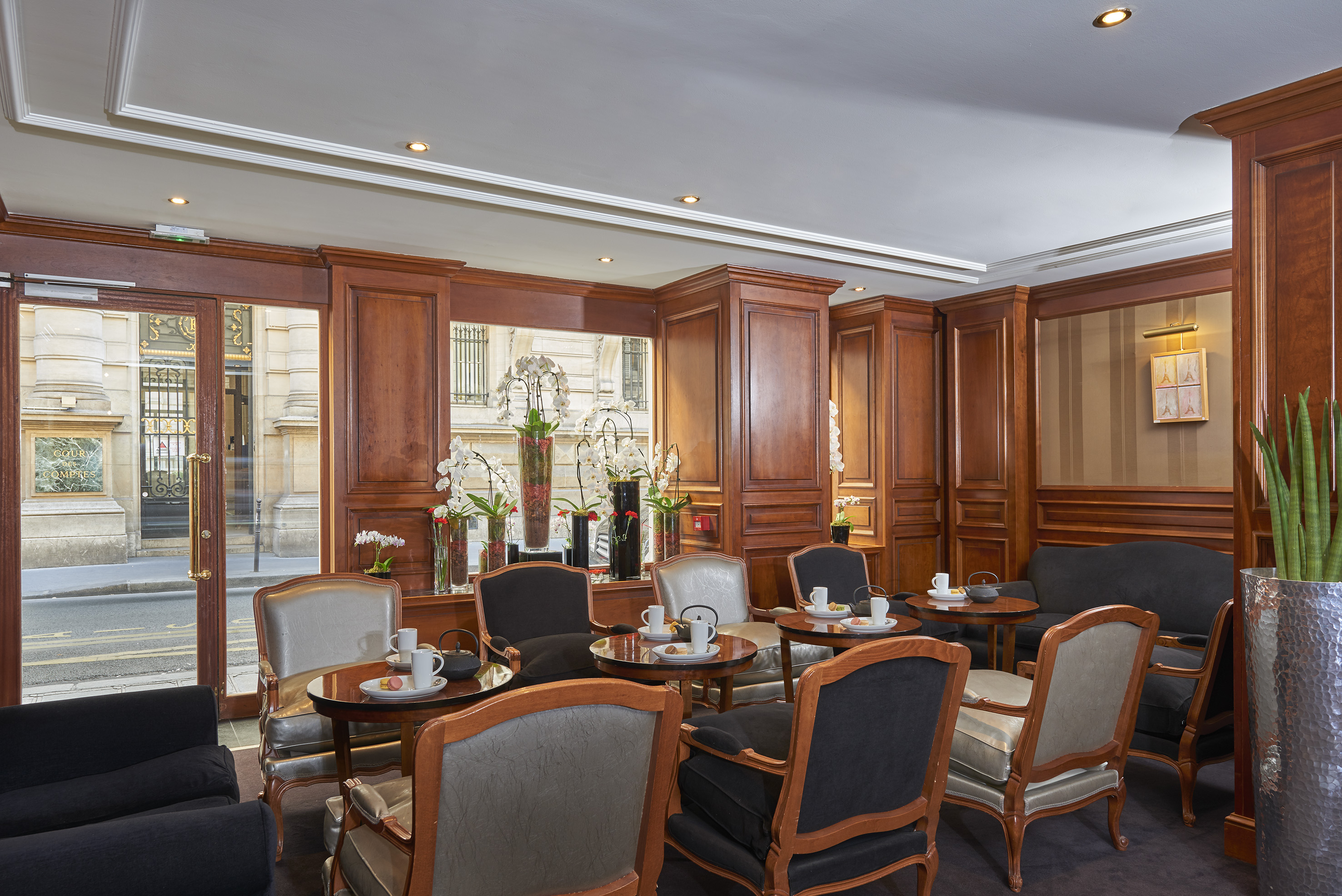 Elegant hotel lounge, wood panels, comfy chairs, tea service, city view.