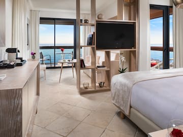 a room with a television and a view of the ocean