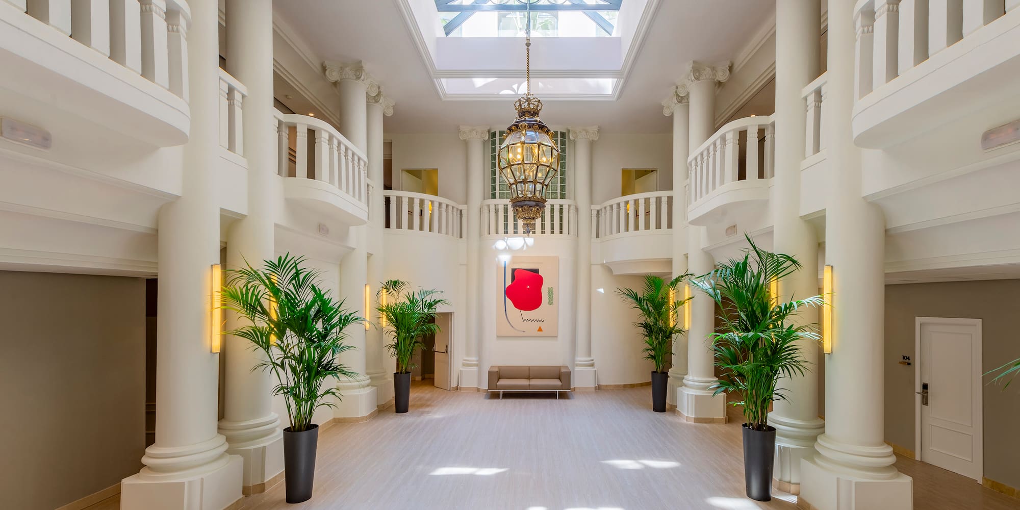 a large white room with columns and plants
