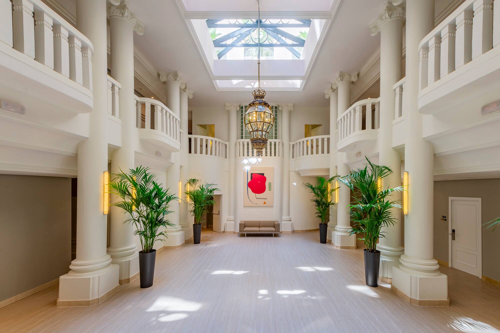 Elegant hotel atrium with classical columns, skylight, and large chandelier.