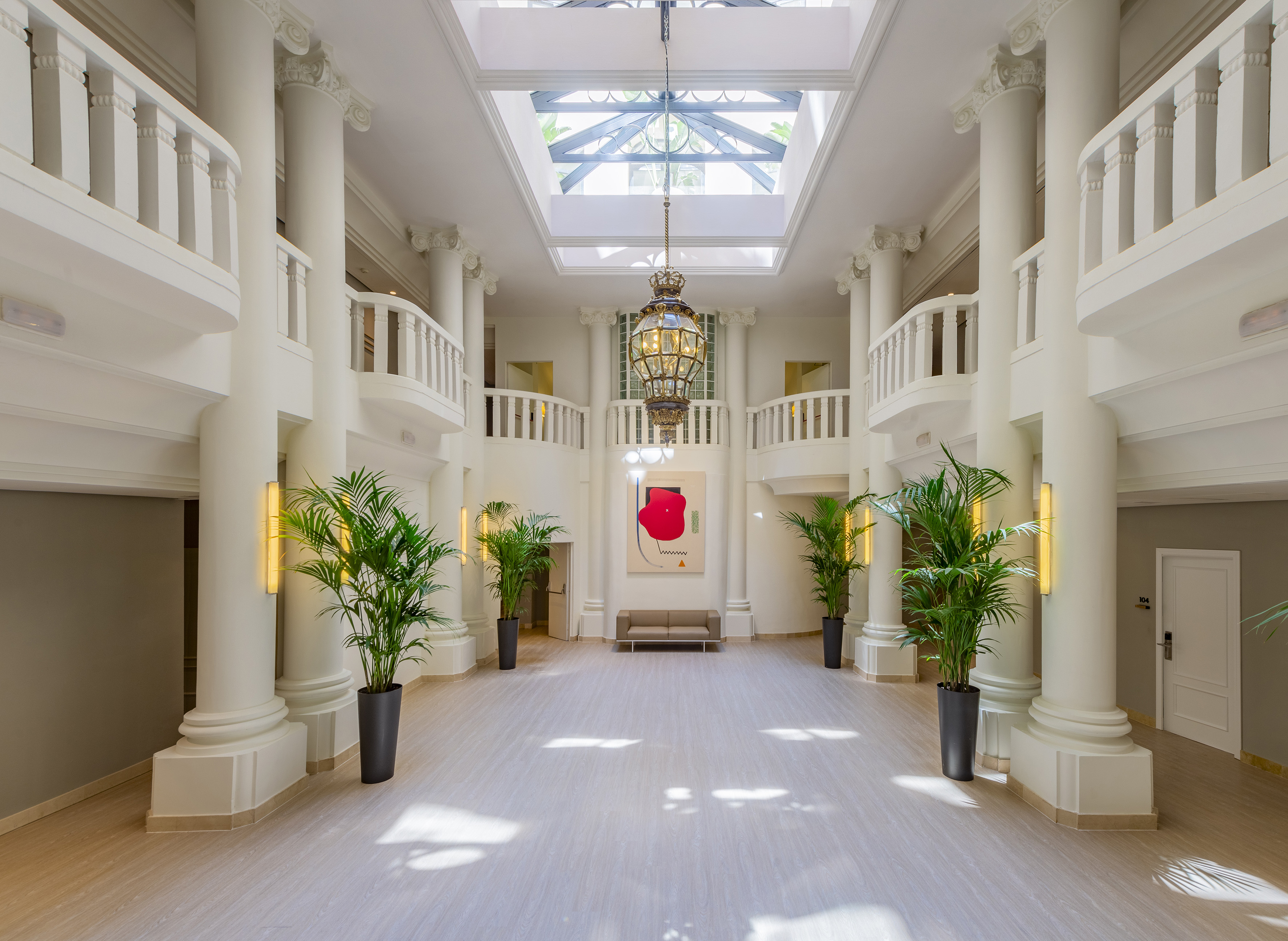 Elegant hotel atrium with classical columns, skylight, and large chandelier.