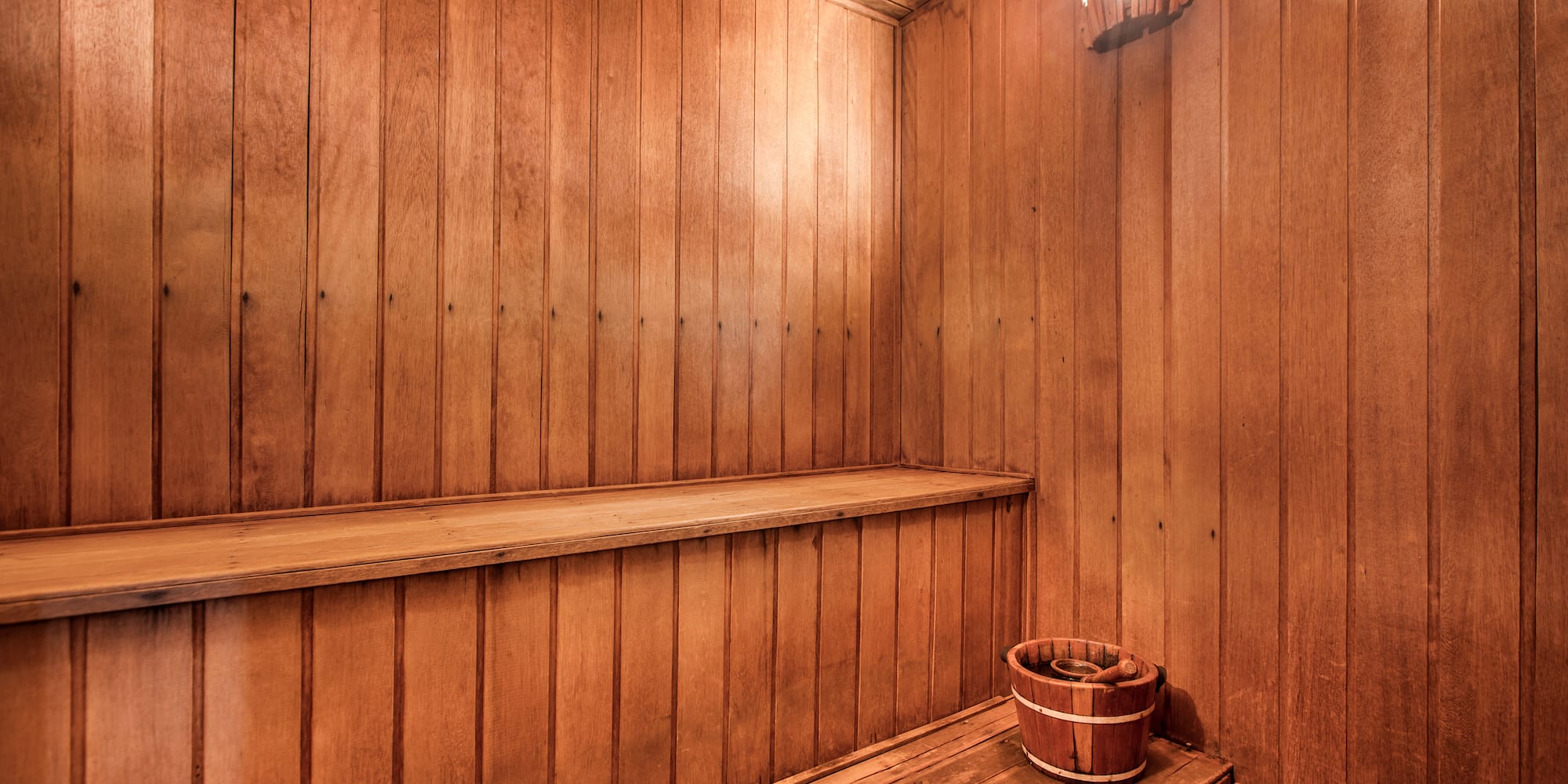 a wooden sauna with a bucket and bucket on a bench