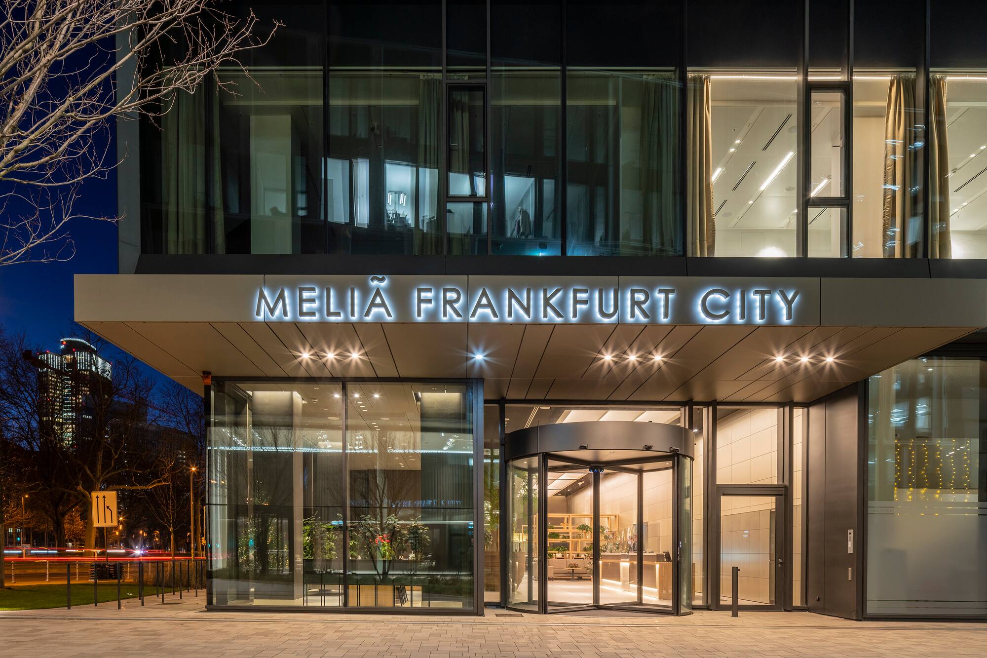 Meliã Frankfurt City hotel entrance at night, with illuminated sign and revolving door.