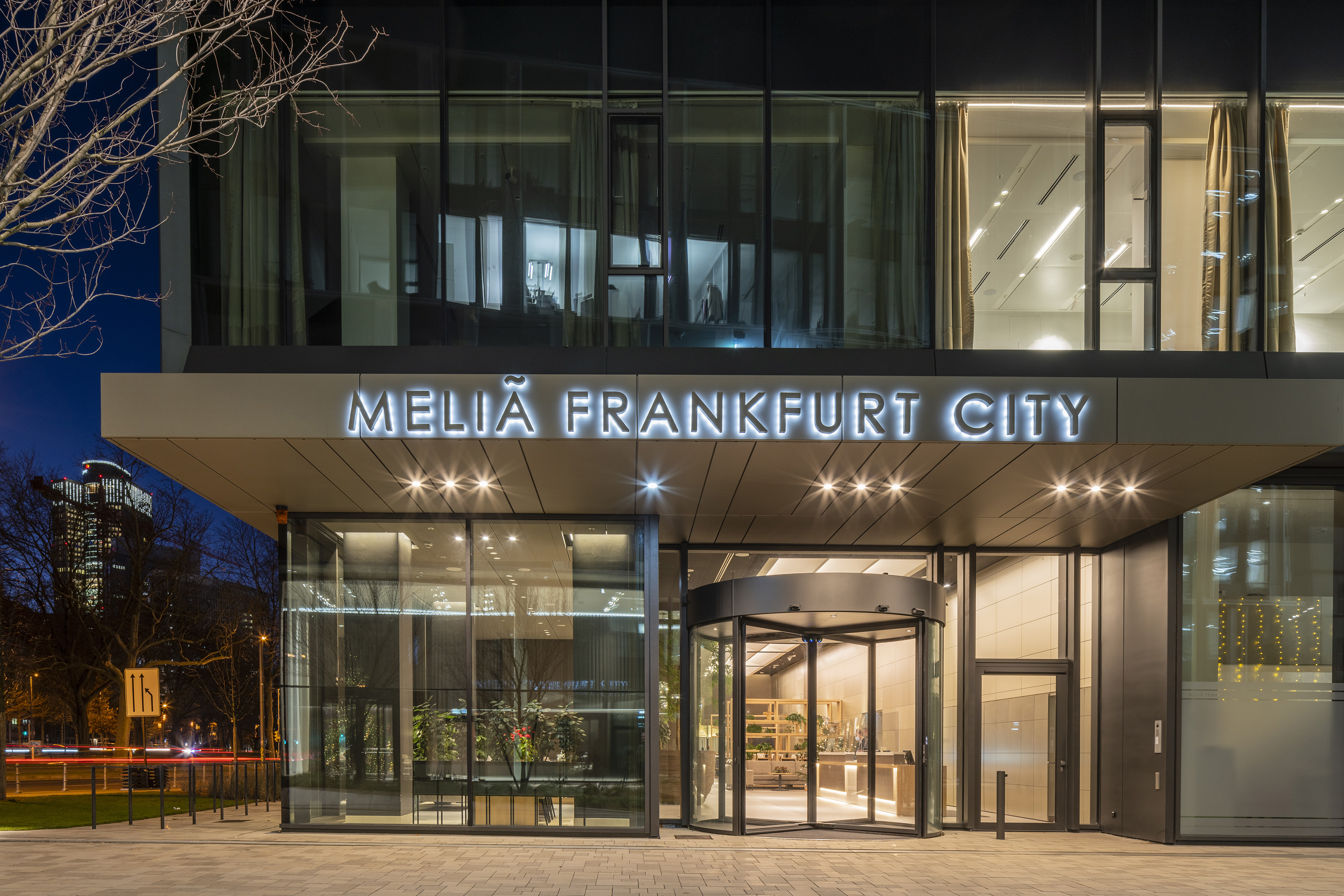 Meliã Frankfurt City hotel entrance at night, with illuminated sign and revolving door.