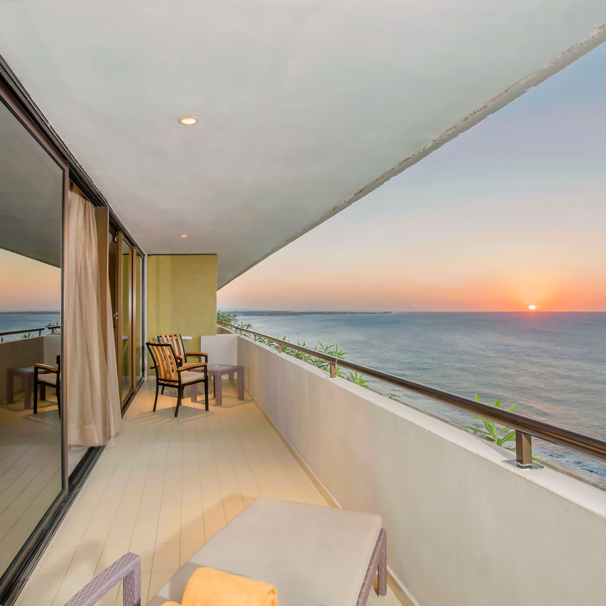 a balcony with chairs and a view of the ocean