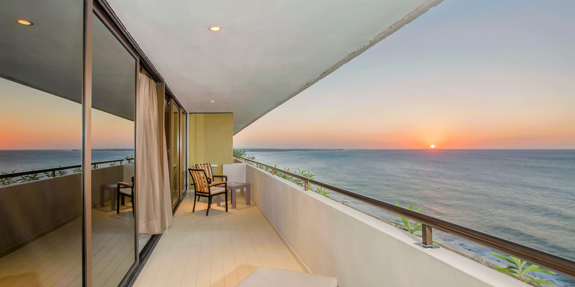 a balcony with chairs and a view of the ocean