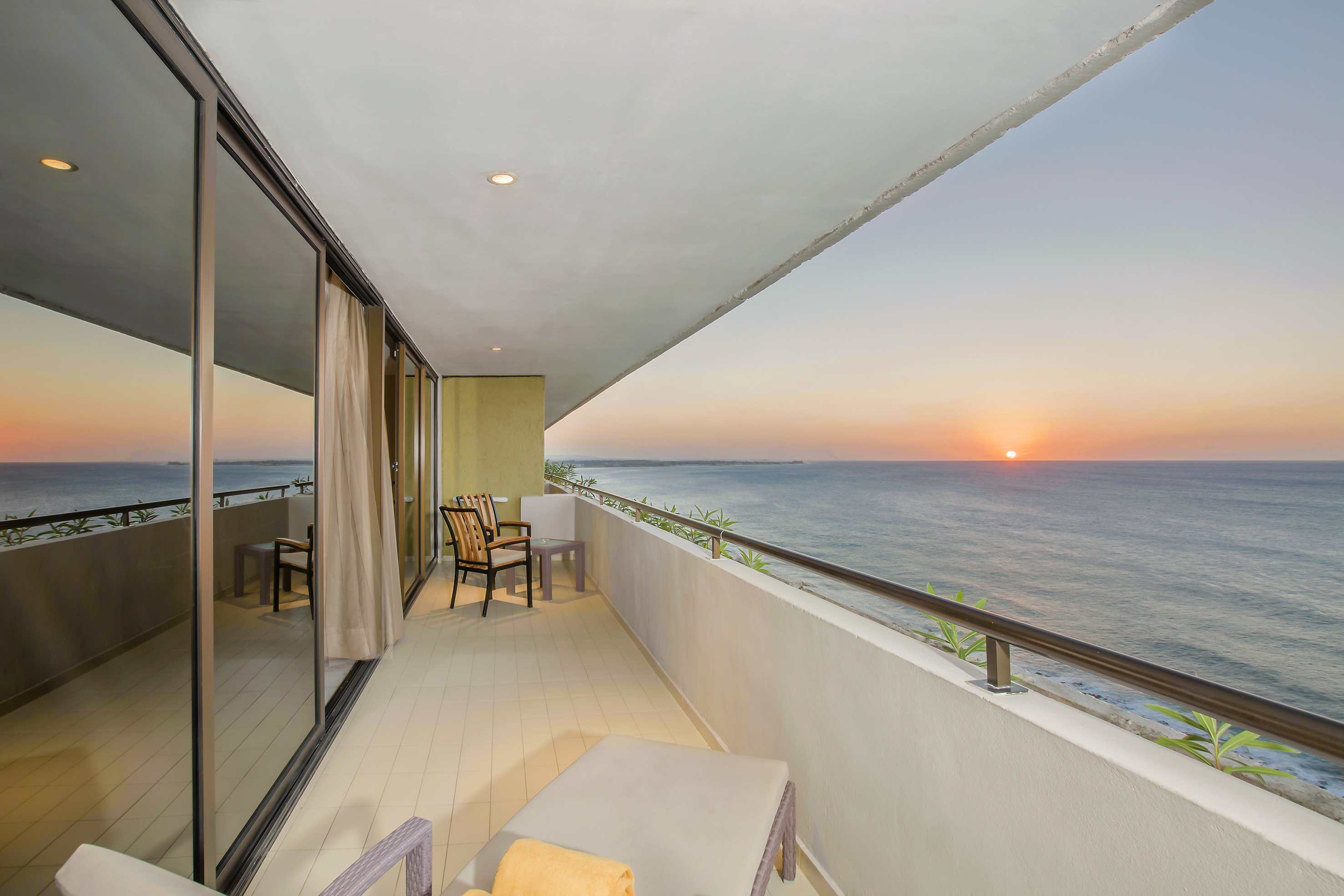 a balcony with chairs and a view of the ocean