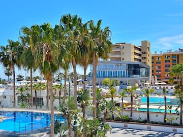 a pool with palm trees and buildings in the background