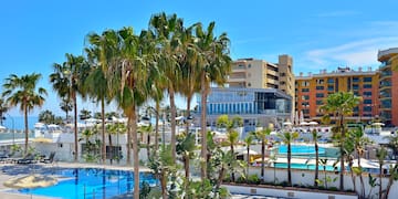 a pool with palm trees and buildings in the background