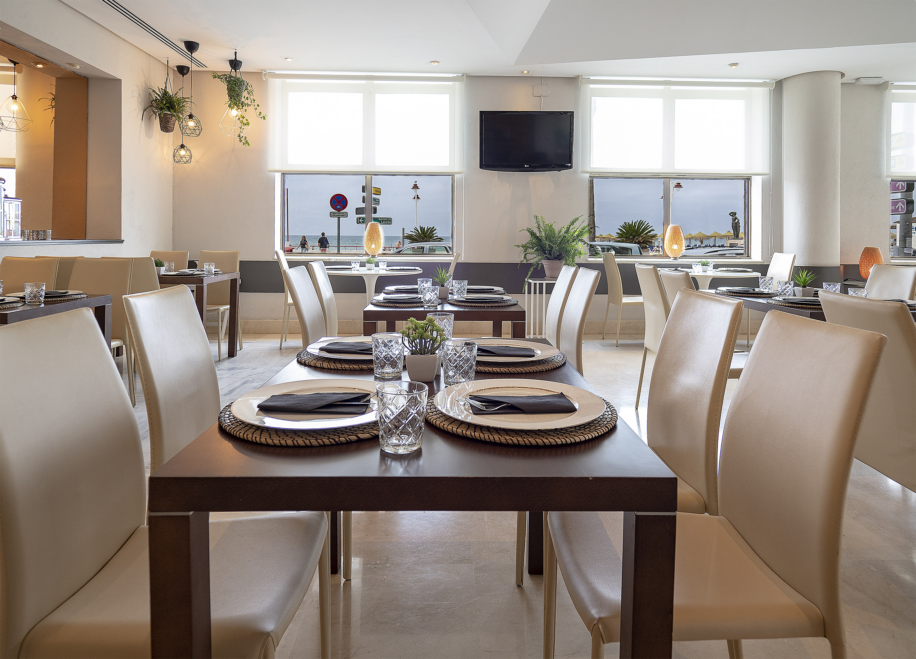 Modern restaurant dining room with set tables and coastal sea view.