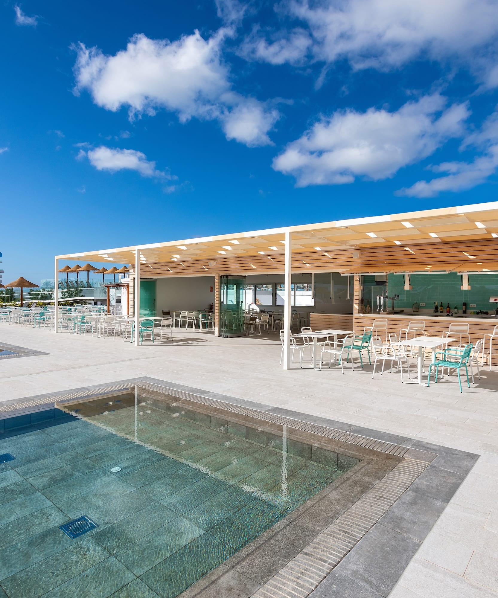 a pool and a building with tables and chairs