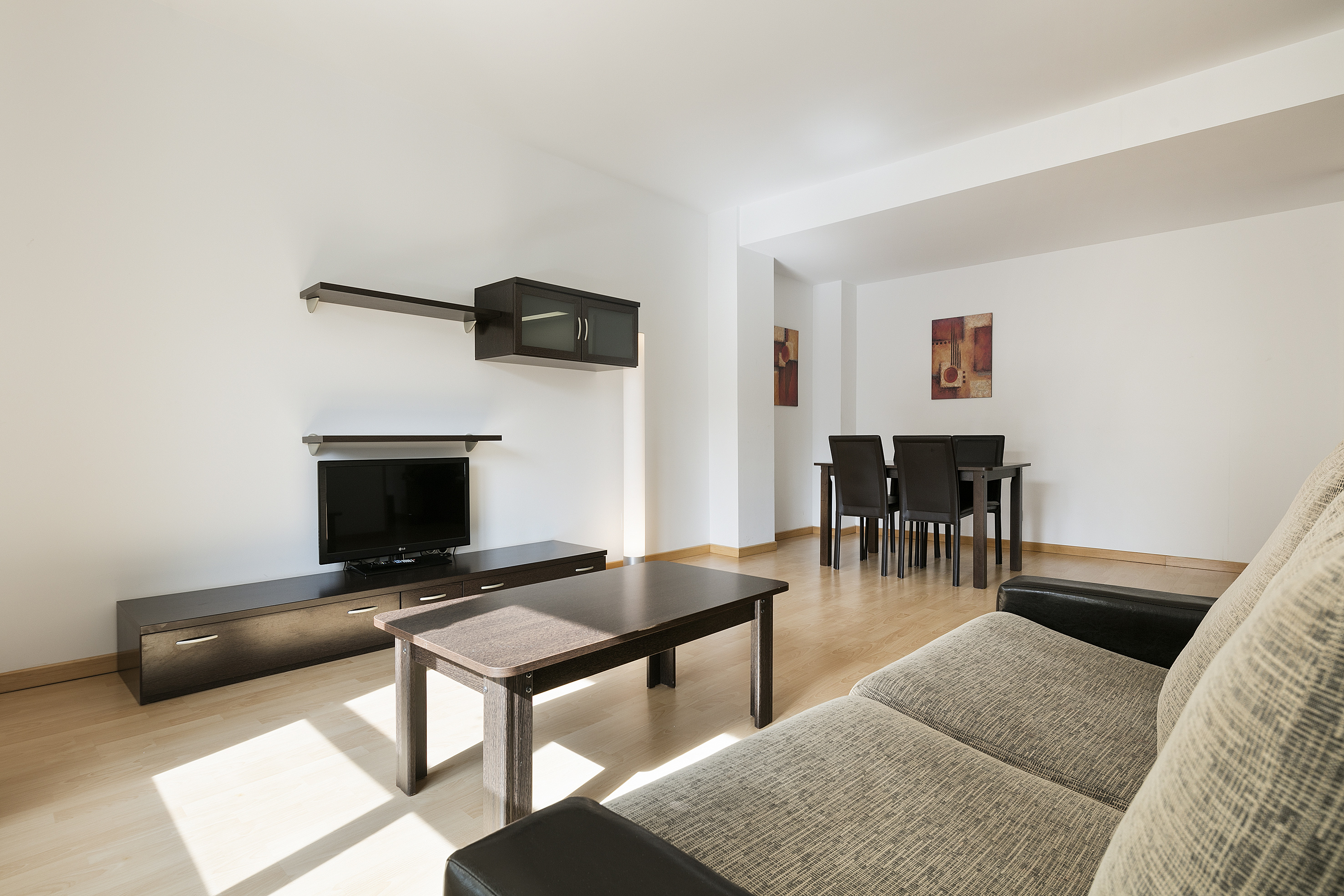Modern living room and dining area with sofa, TV, and dark wood furniture.