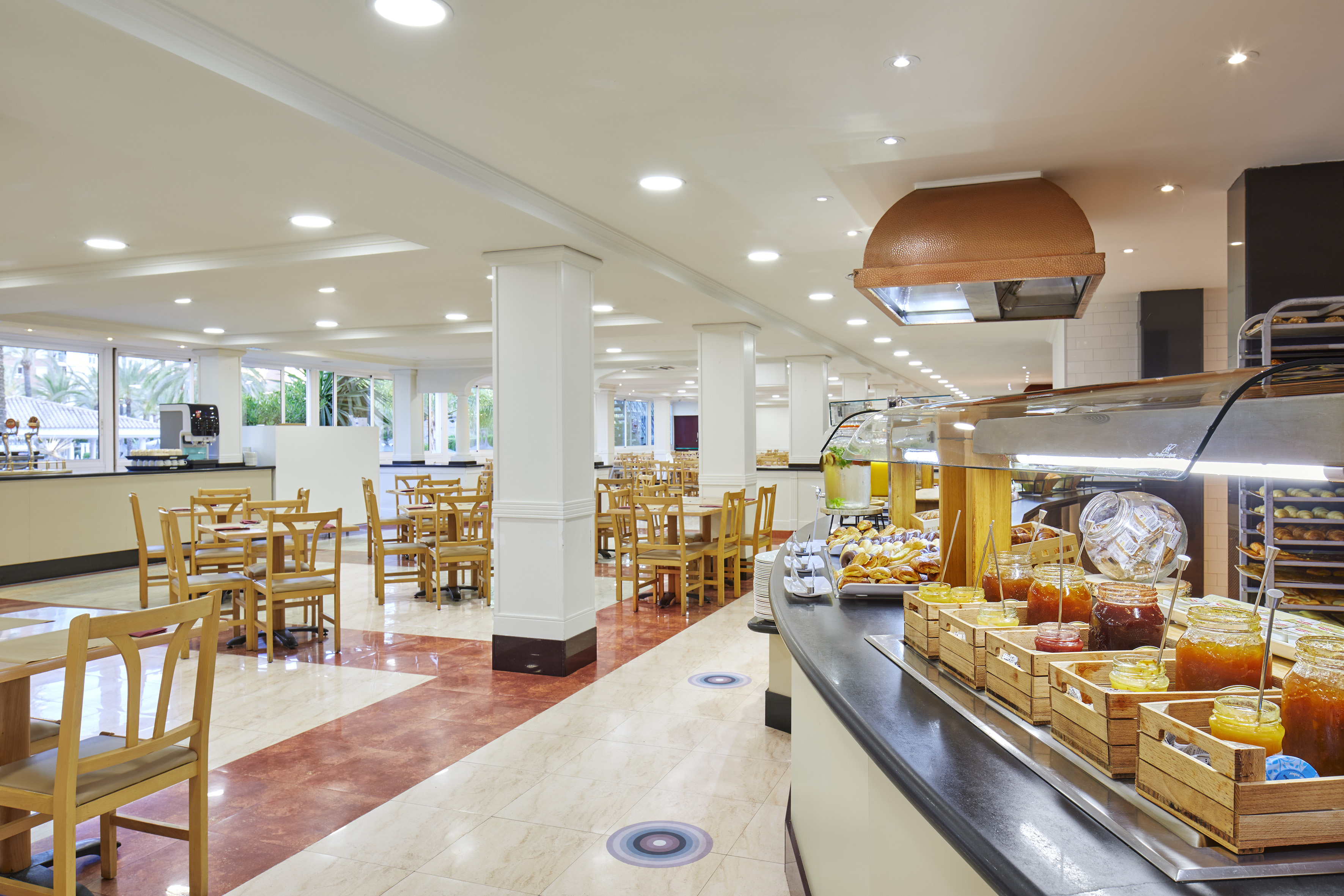 Bright hotel breakfast buffet with pastries, jams, and a spacious dining room.