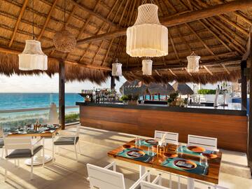 a restaurant with a thatched roof and a beach view