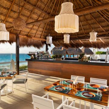 a restaurant with a thatched roof and a beach view