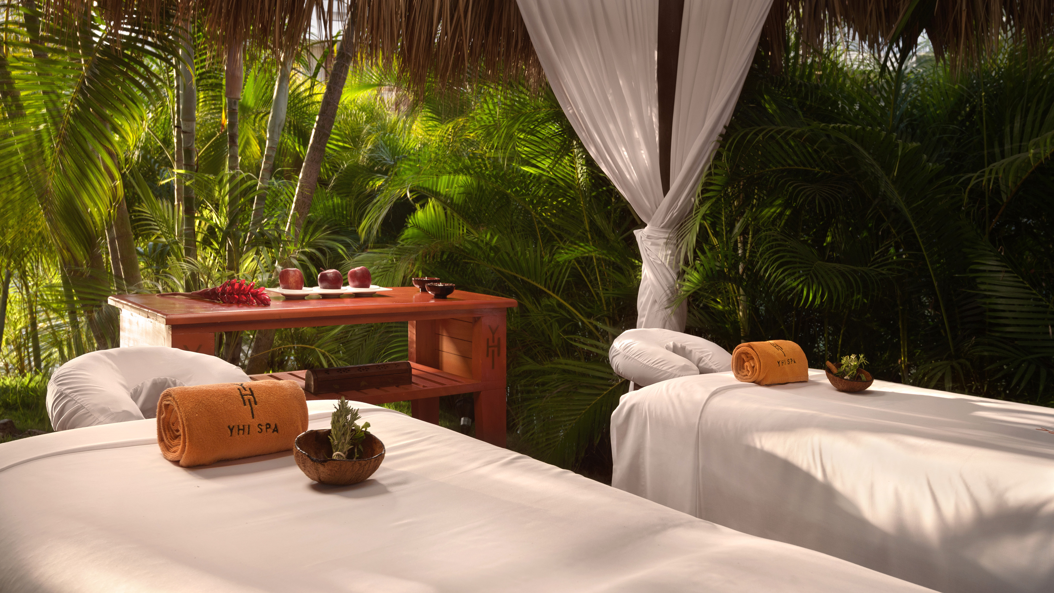 Outdoor tropical spa area with two massage beds and YHI SPA towels.