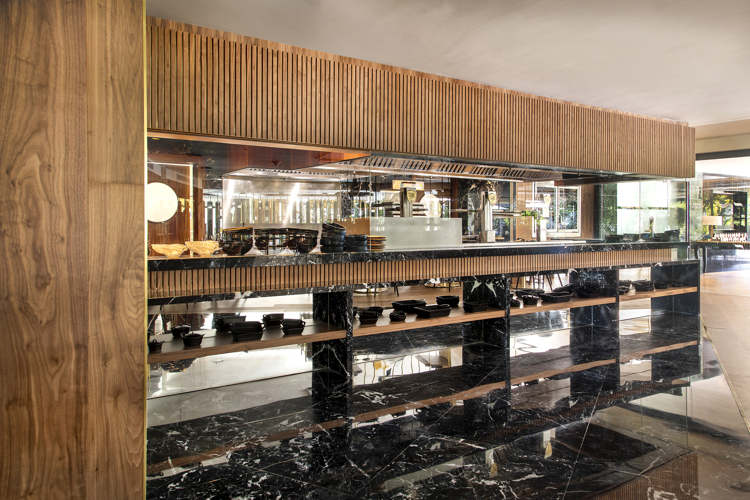Luxury buffet area with black marble, wood slats, and sleek serving dishes.