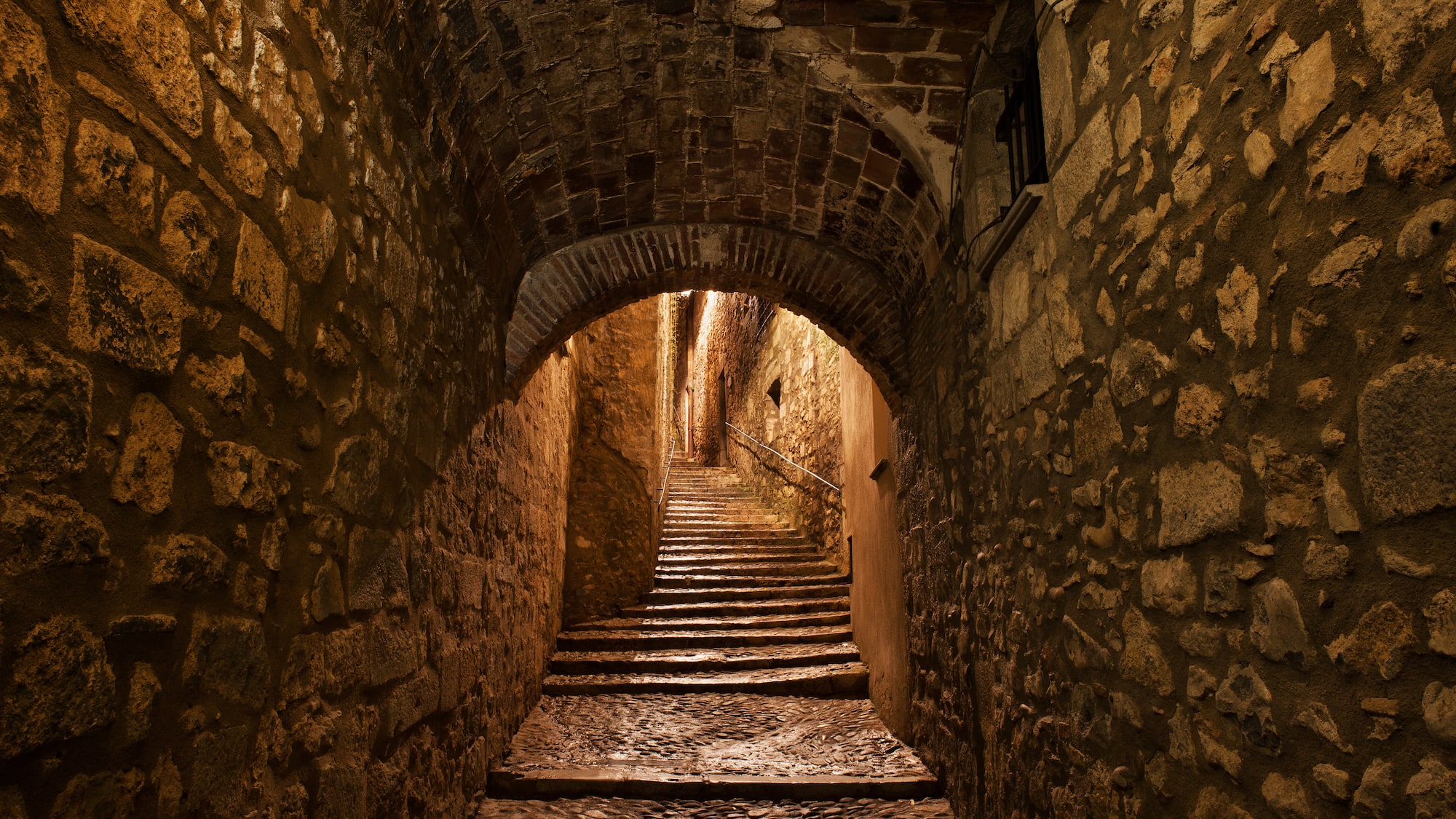 a stone tunnel with stairs and archways