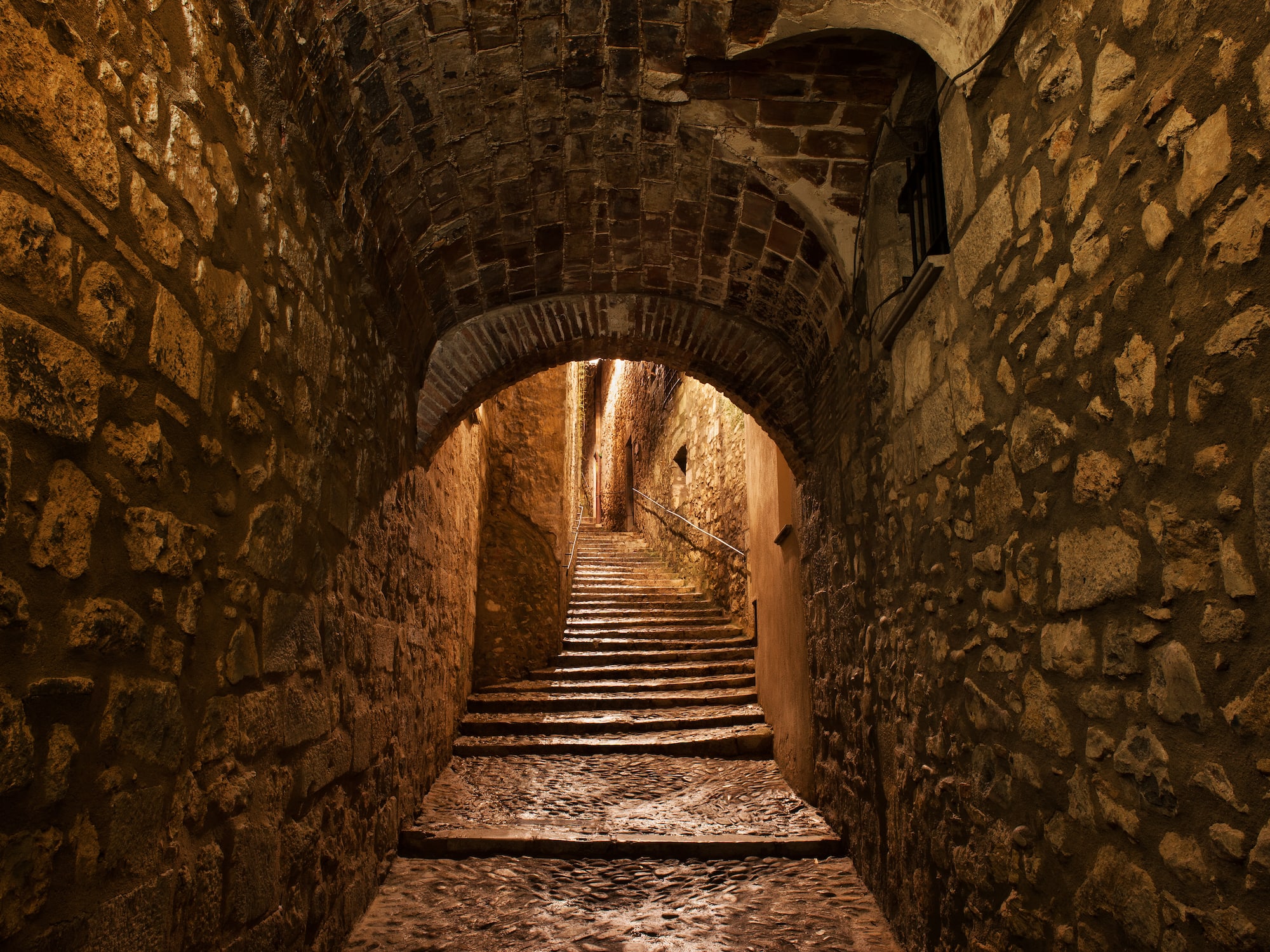 a stone tunnel with stairs and archways