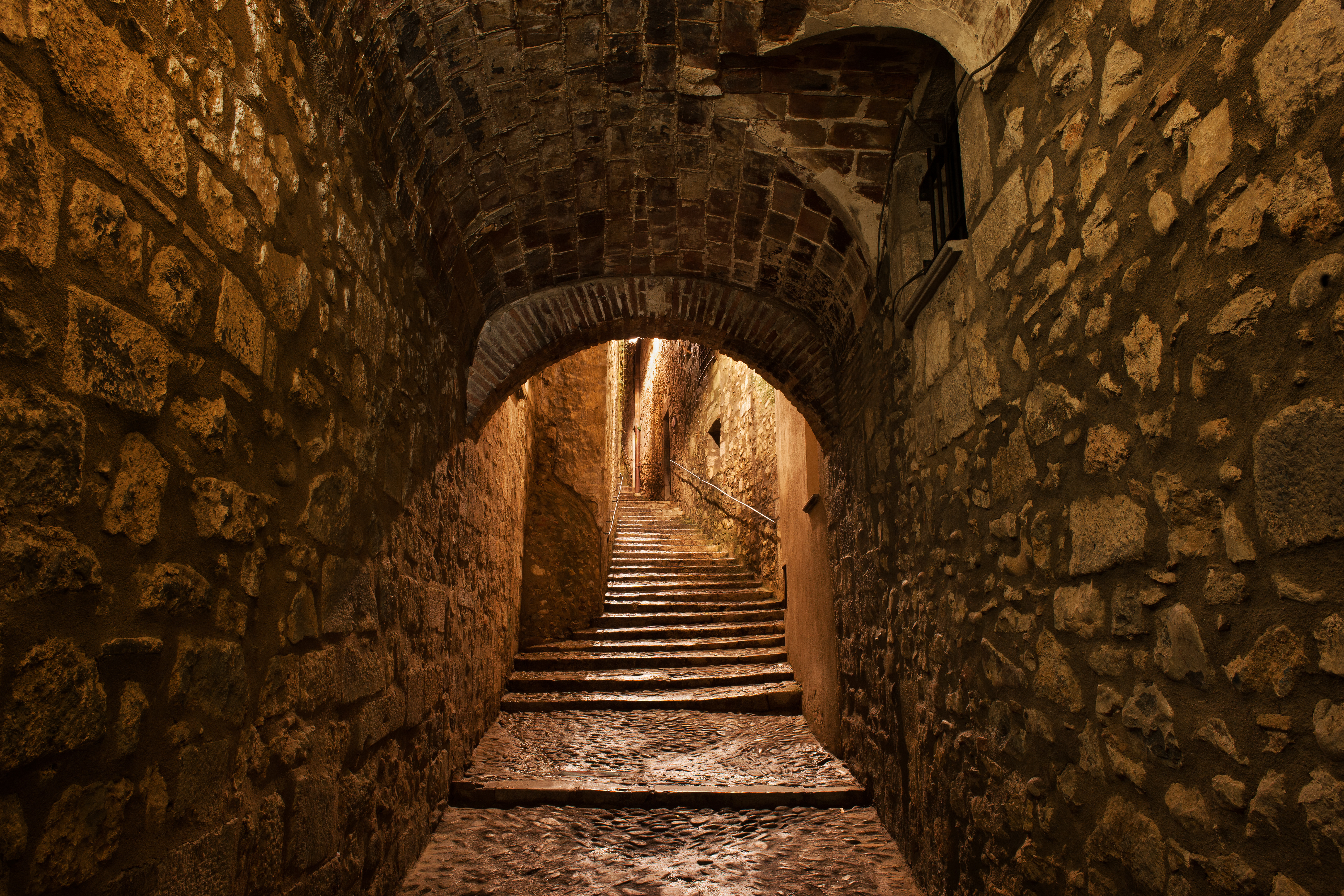 a stone tunnel with stairs and archways