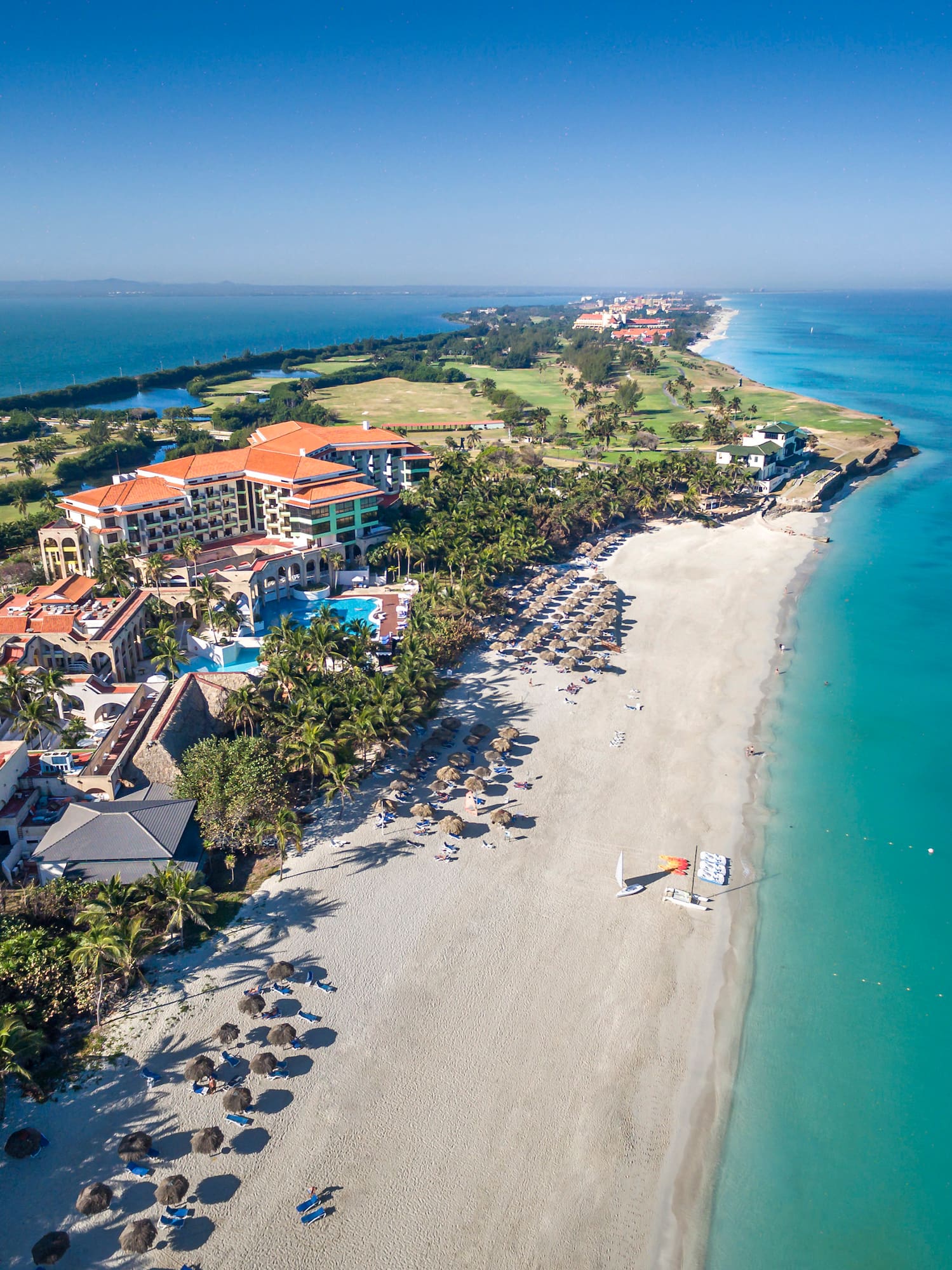 a beach with buildings and a sailboat in the water