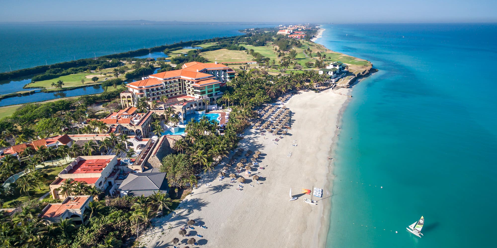 a beach with buildings and a sailboat in the water