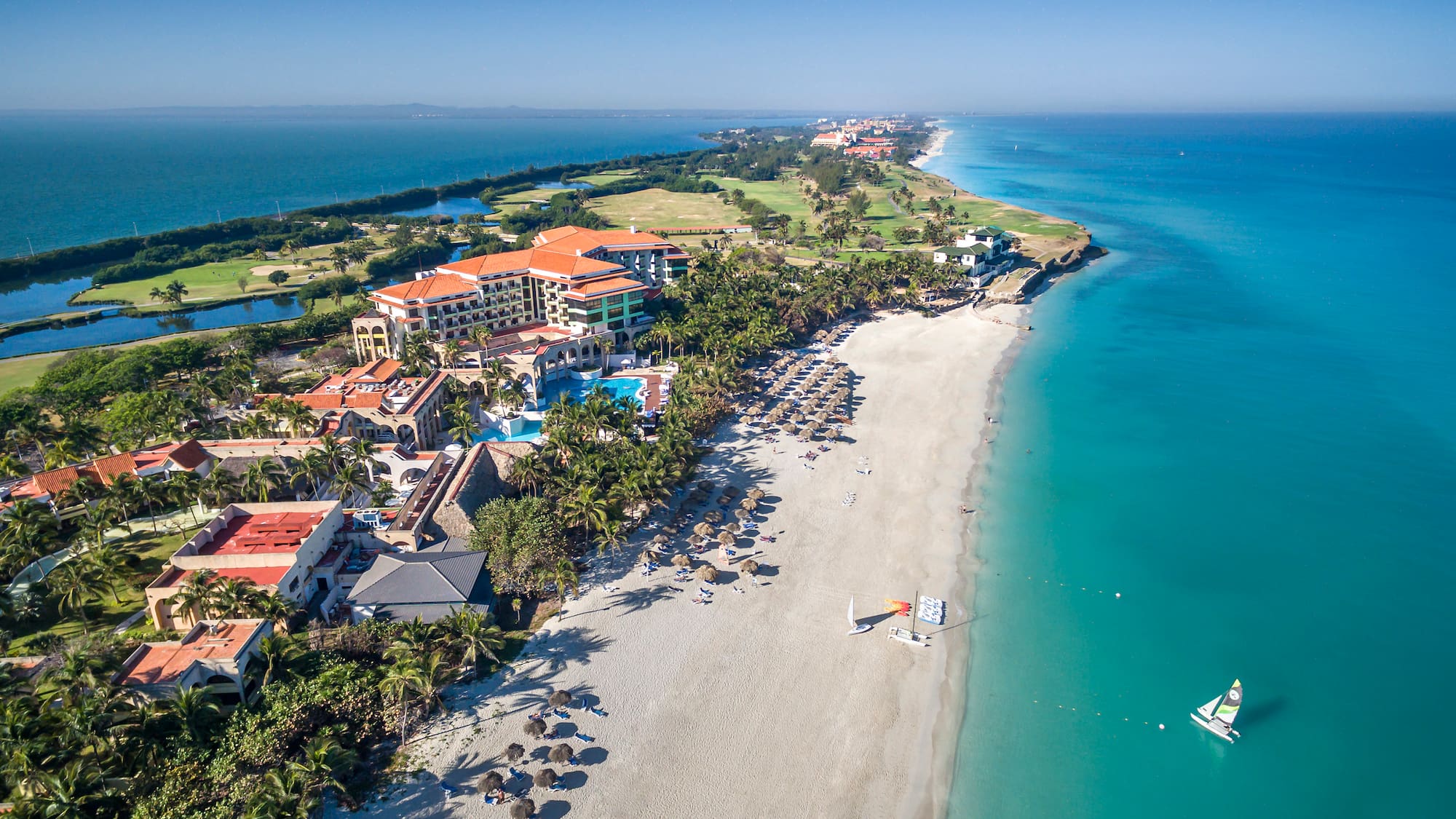a beach with buildings and a sailboat in the water