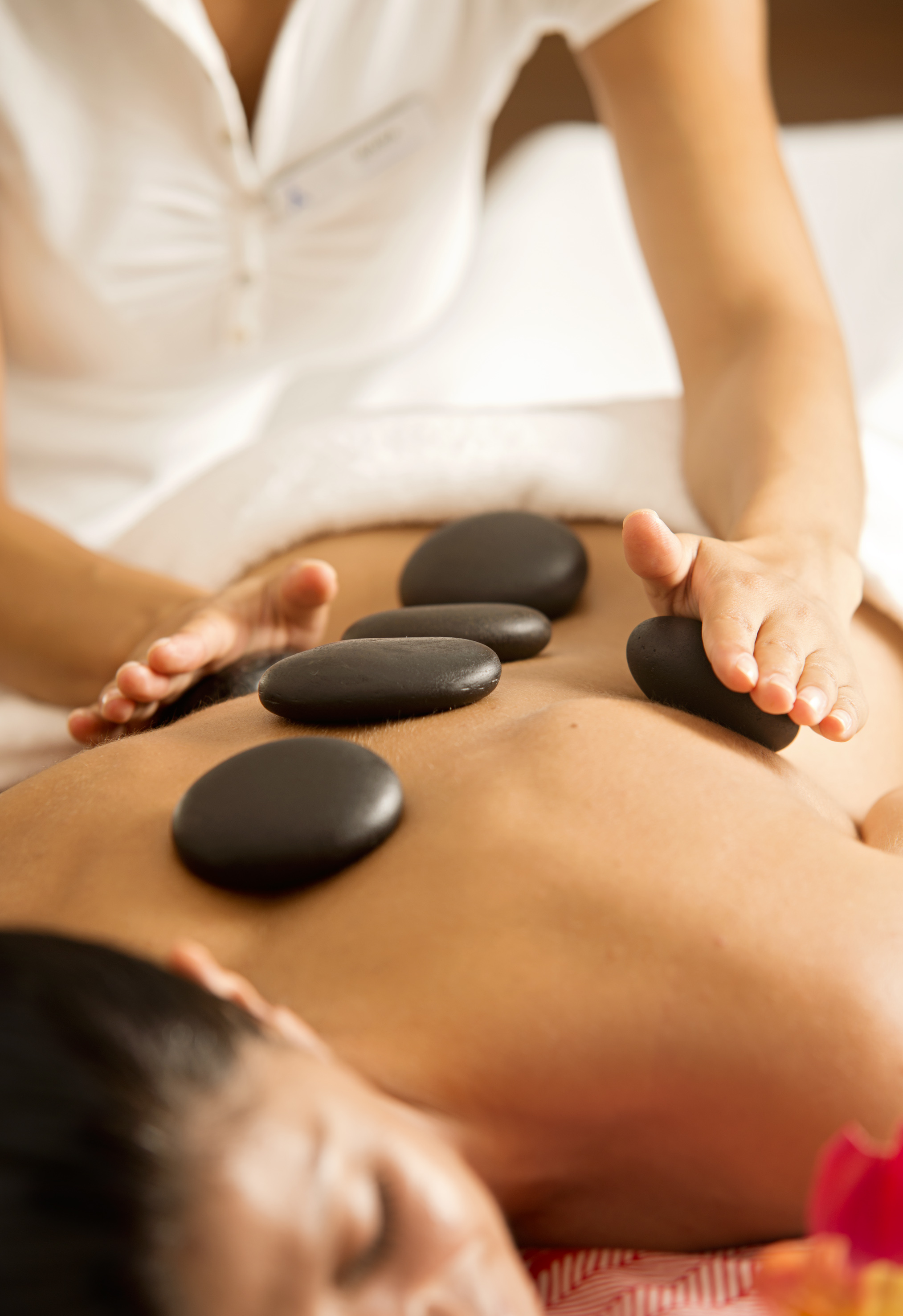 Relaxing hot stone back massage with warm basalt stones at a spa.