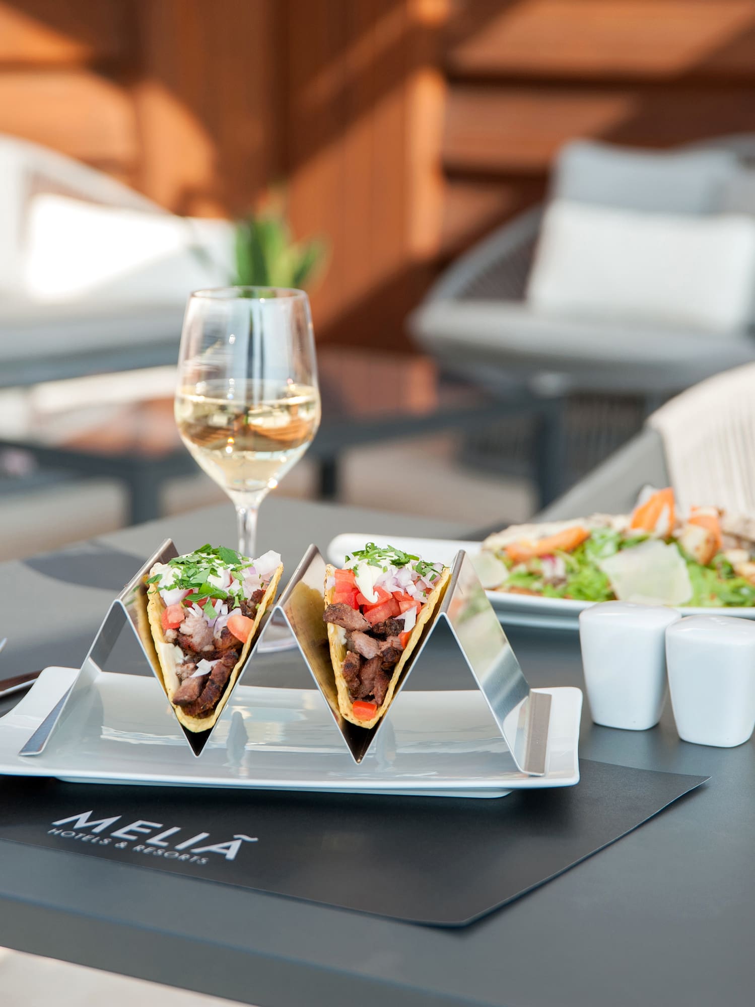 tacos on a plate with a glass of wine on a table