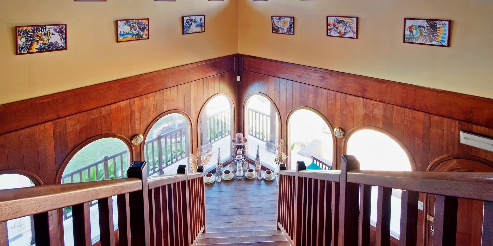 a staircase with a chandelier and art on the wall