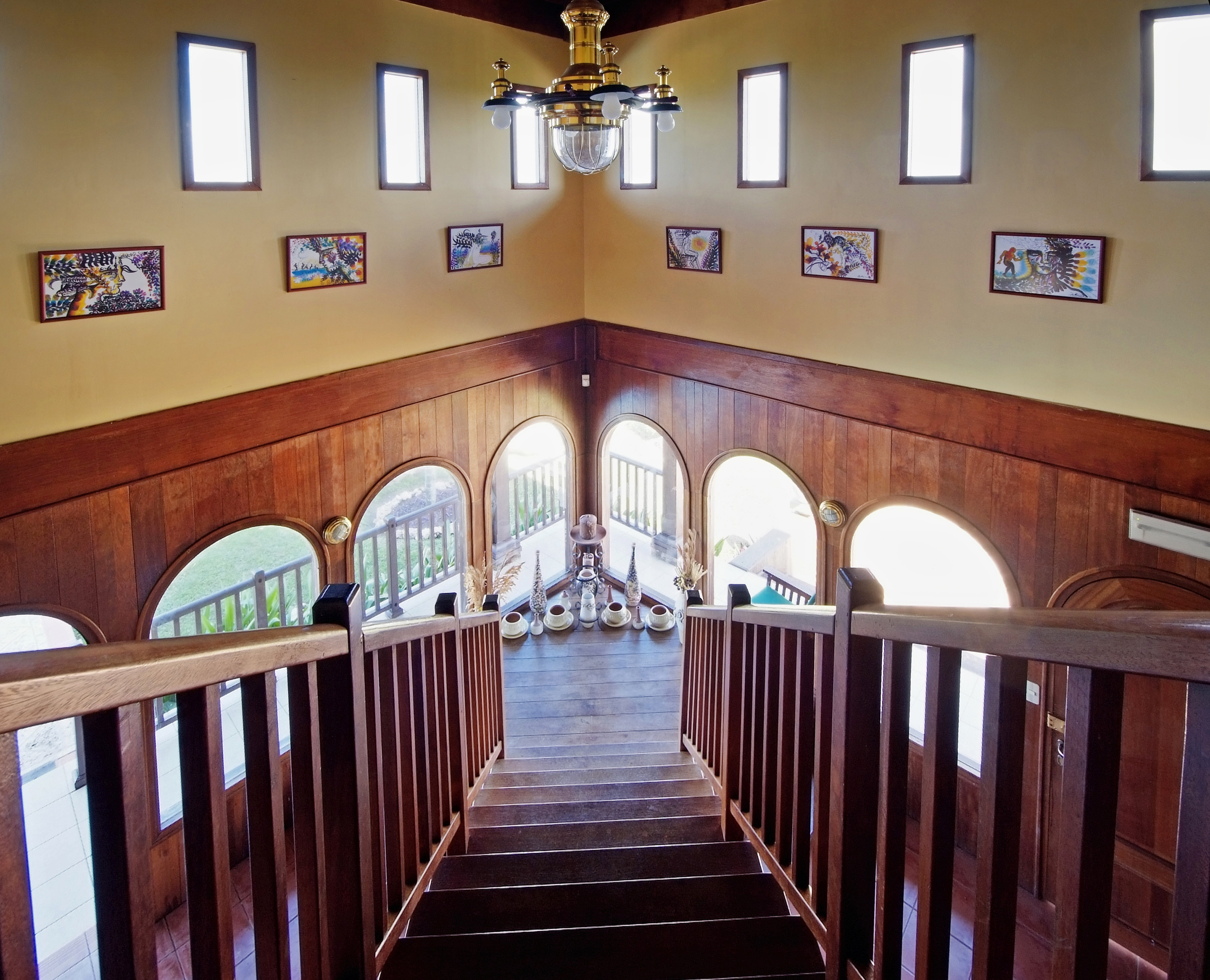 a staircase with a chandelier and art on the wall