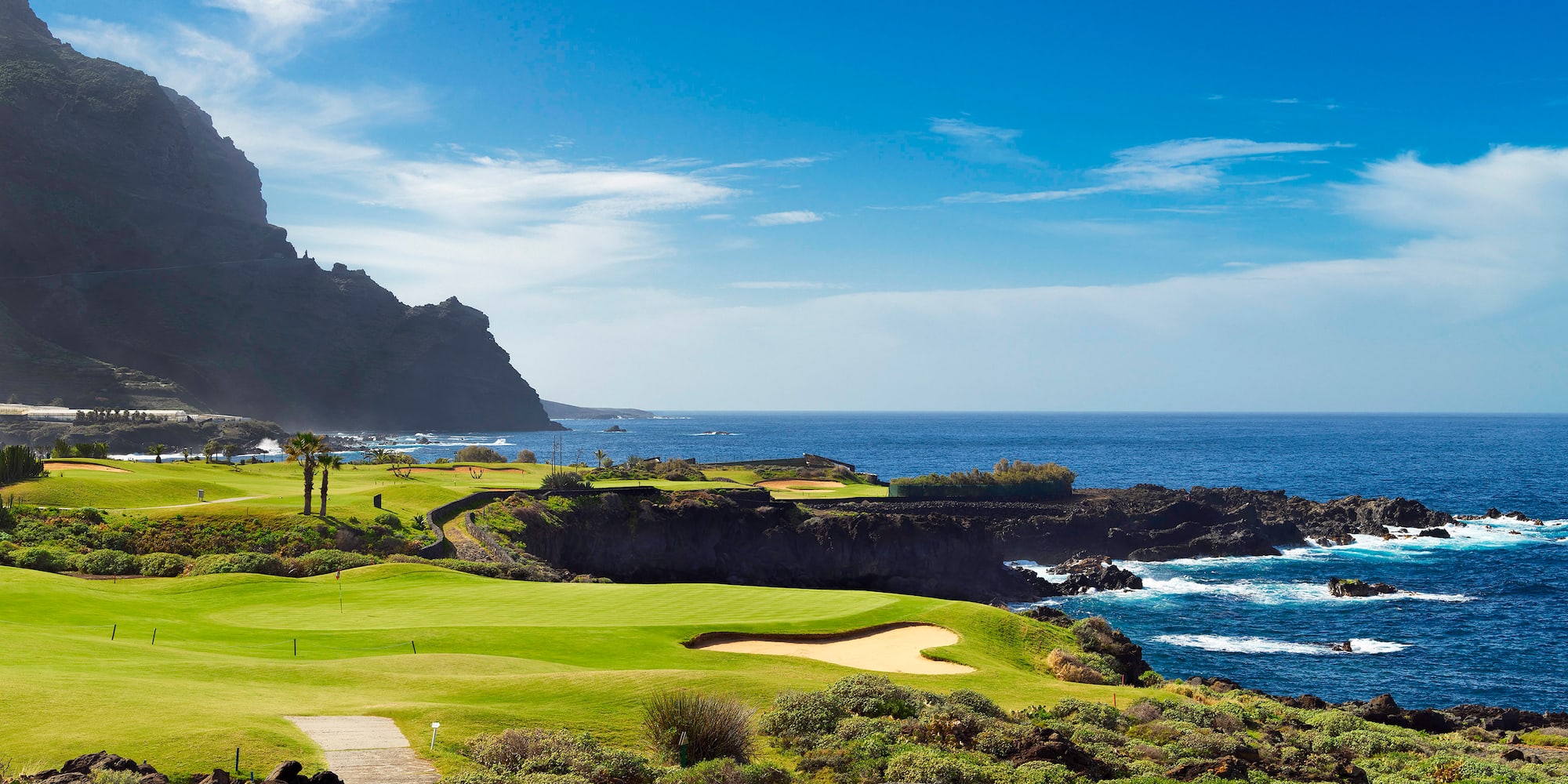 a golf course with a body of water and a hill