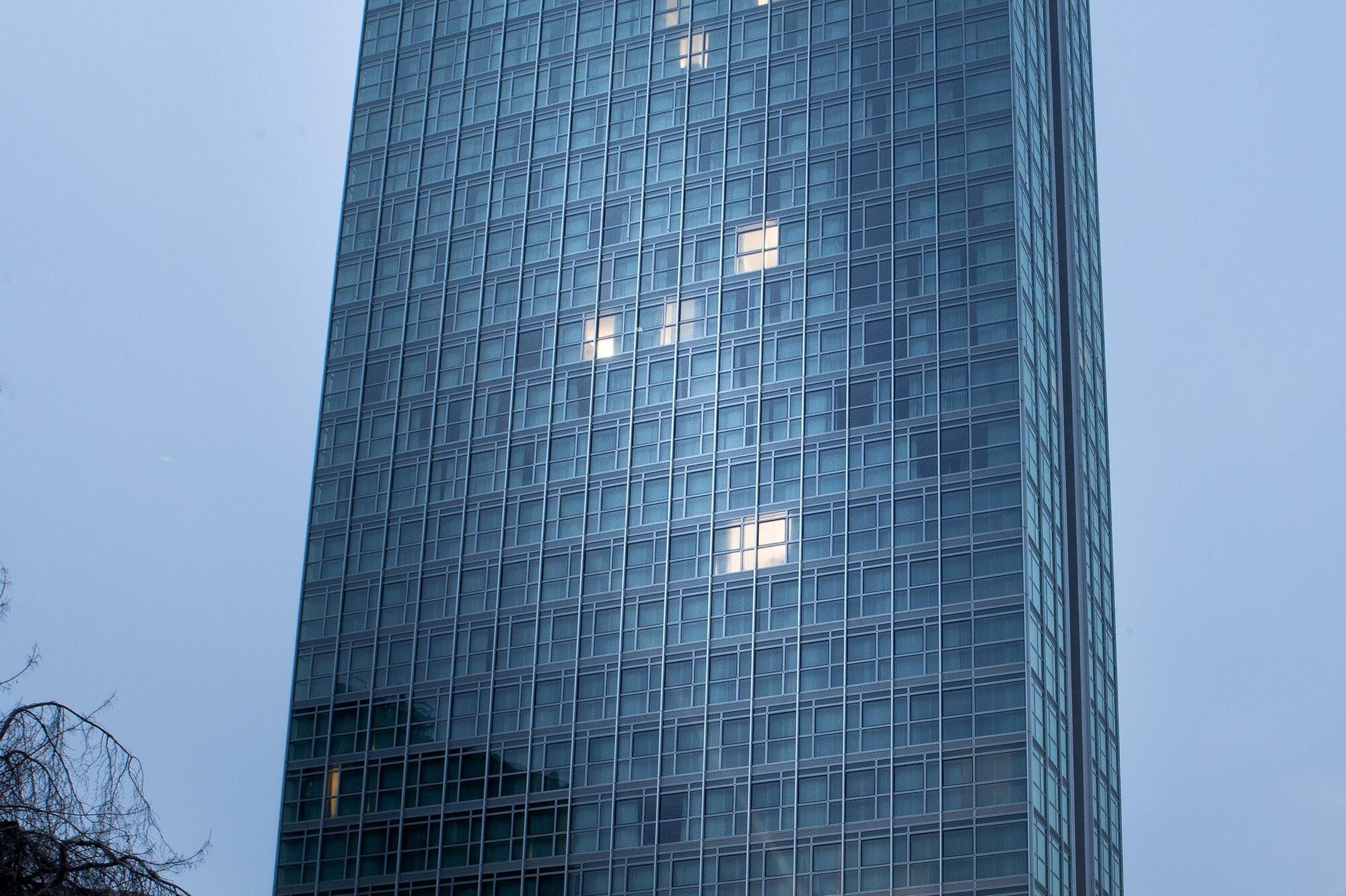 Modern glass skyscraper illuminated at dusk with light trails from city traffic.