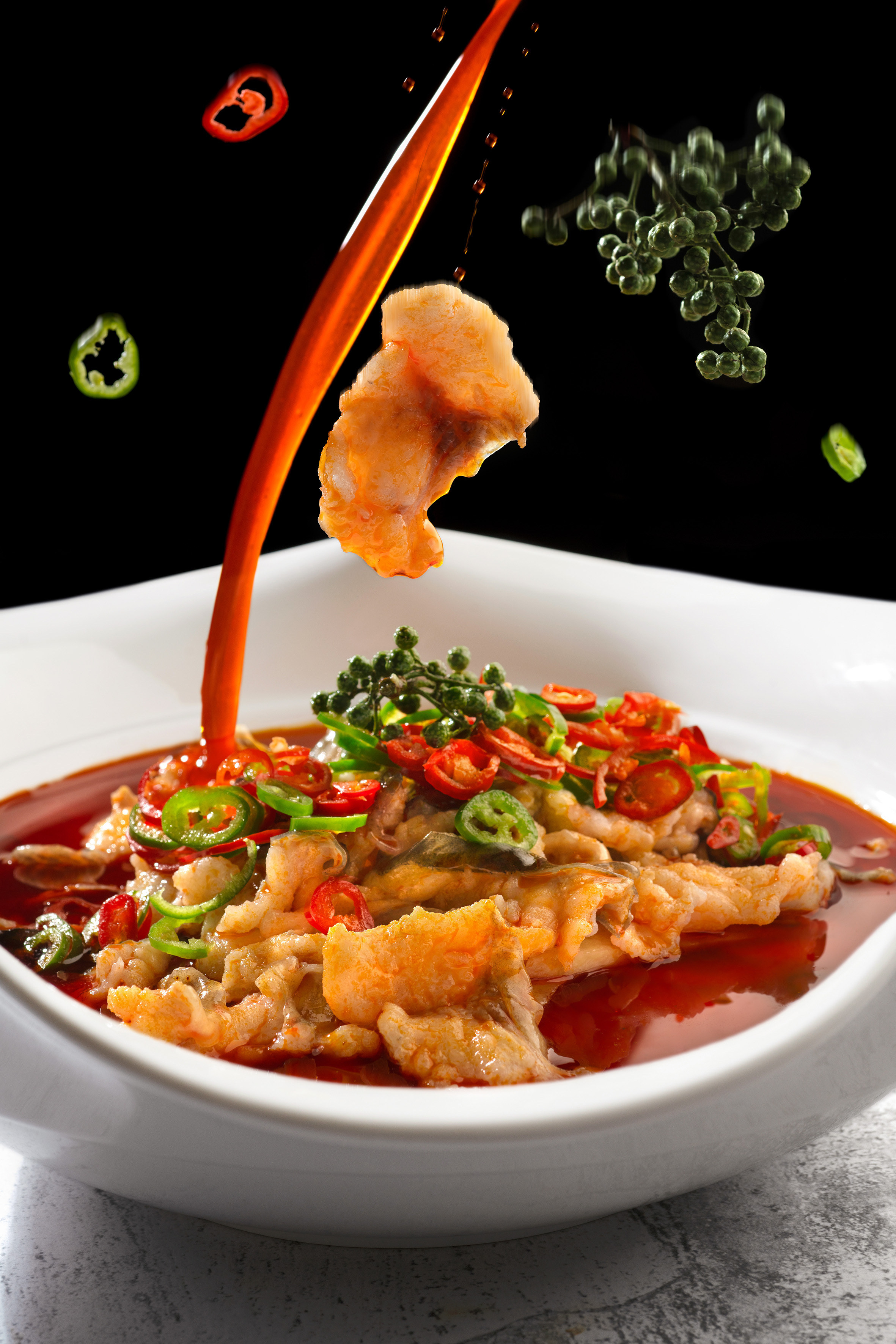 Sichuan Boiled Fish with pouring chili oil, green peppercorns, peppers.