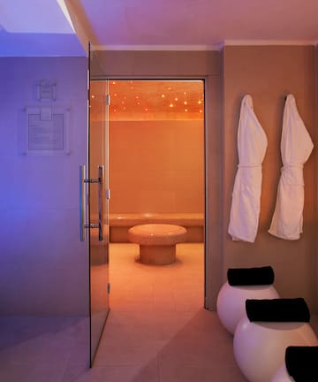 a bathroom with white bath robes and a glass door