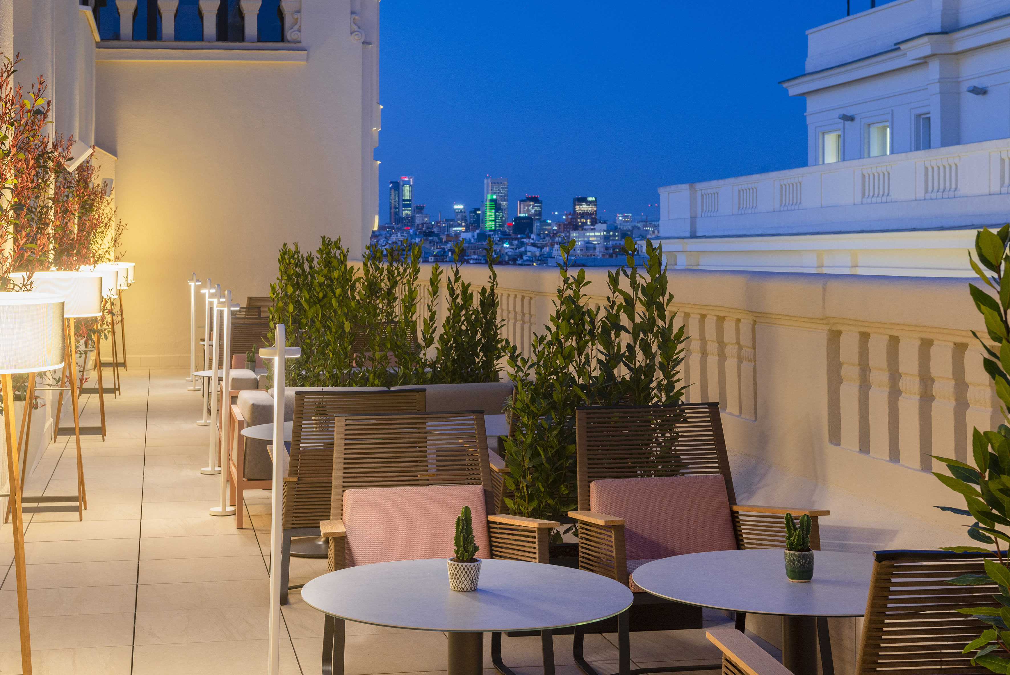 Evening rooftop terrace with city views, outdoor seating, and warm lighting.