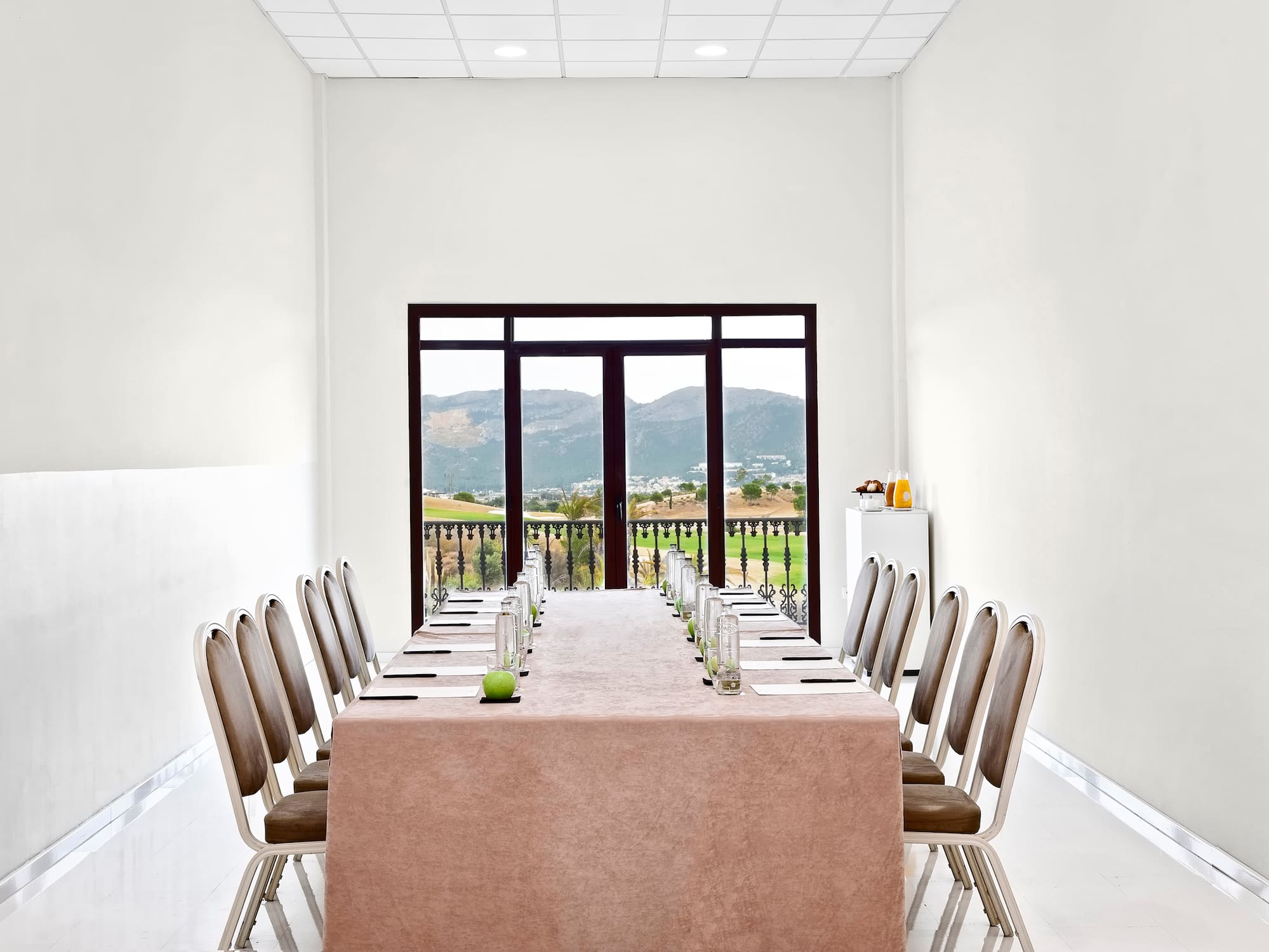 a table with chairs and a tablecloth in a room with a view of the mountains