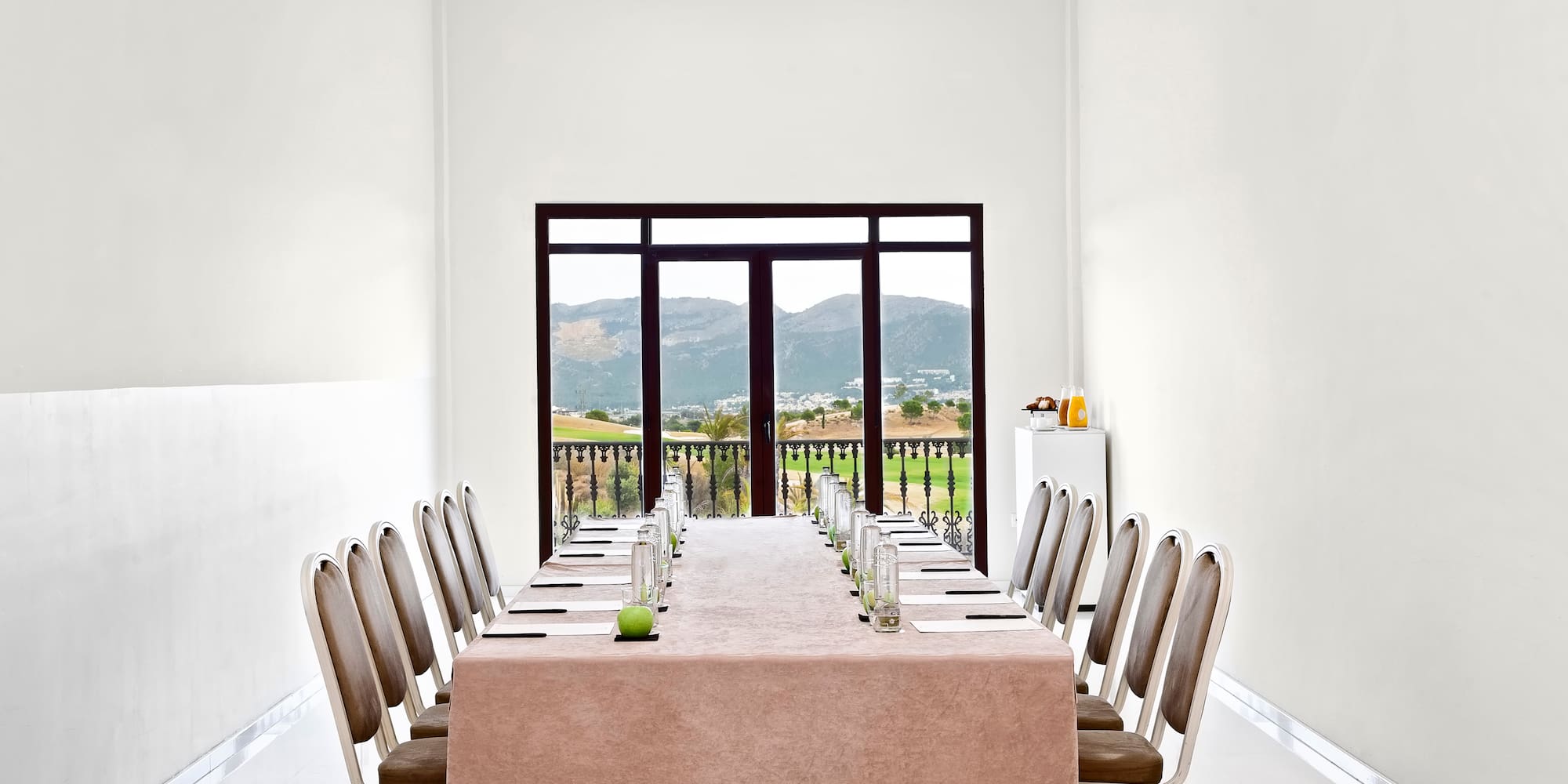 a table with chairs and a tablecloth in a room with a view of the mountains