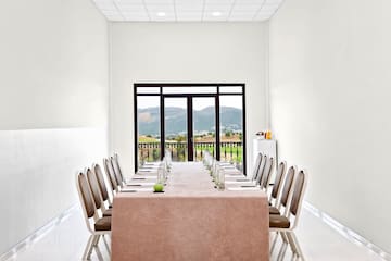 a table with chairs and a tablecloth in a room with a view of the mountains