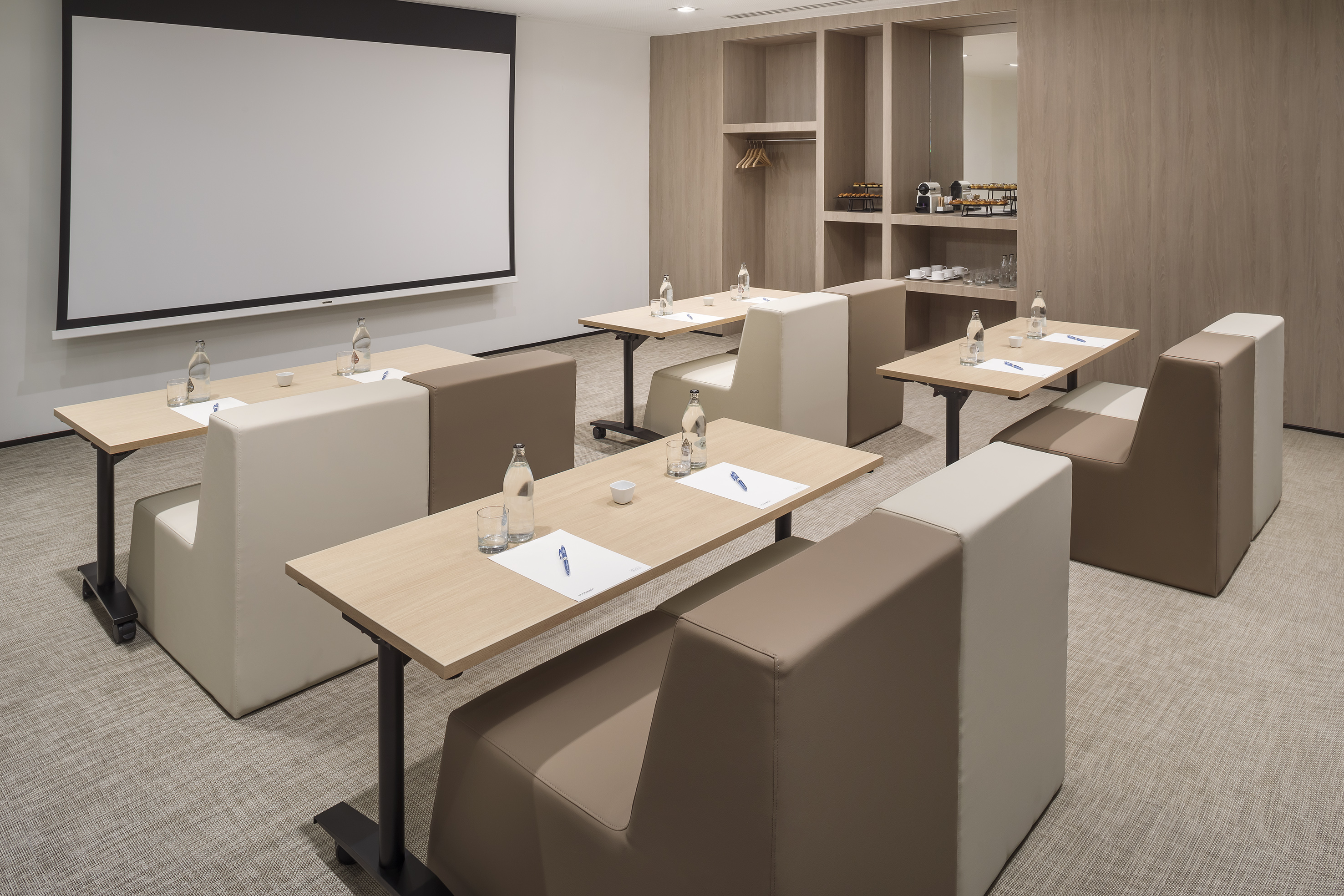 Contemporary meeting space for corporate events with screen and tables.